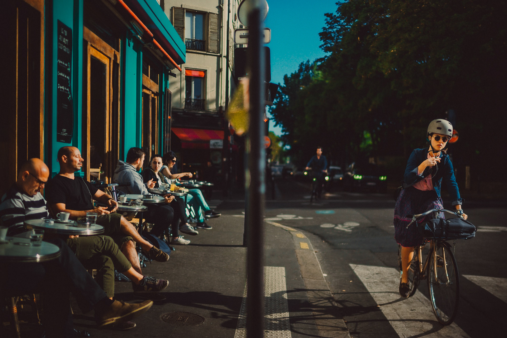 A woman riding a bike in front of a café, Canal Saint-Martin, Paris, France, September 2017, Leica M.