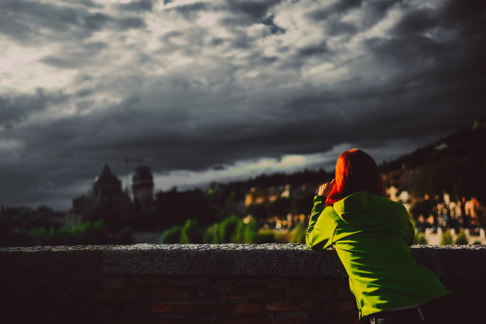 A girl with red hair and a bright green jacket under a gloomy sky in Ponte Pietra Bridge, Verona, Italy, September 2017, Leica M.