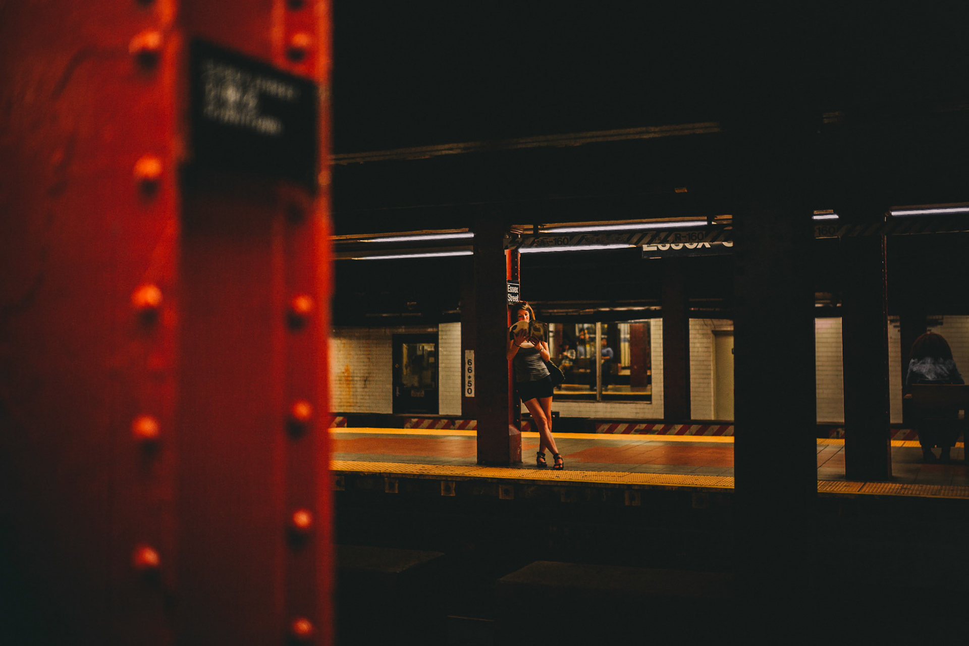 A lone woman reading a magazine on the Essex St Subway Platform, Manhattan, New York City, USA, September 2015, Leica M.