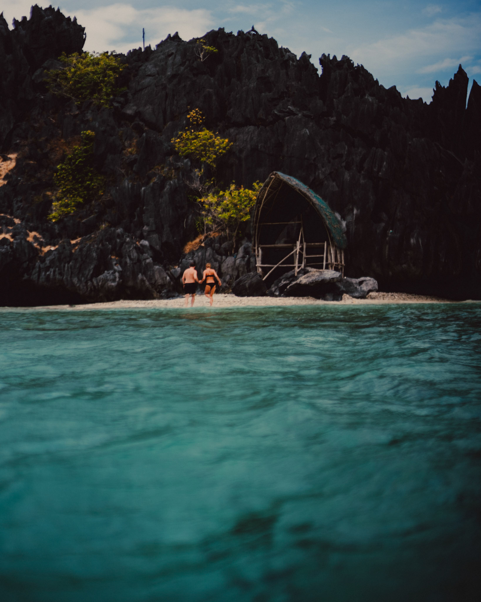 Travel and adventure couple portraits with Skipper Charters, on a cove with a hidden beach with turquoise blue water surrounded by limestone cliffs, Star Beach, Tapiutan Island, El Nido, Palawan, Philippines,Southeast Asia, March 2019, Sony A7III.