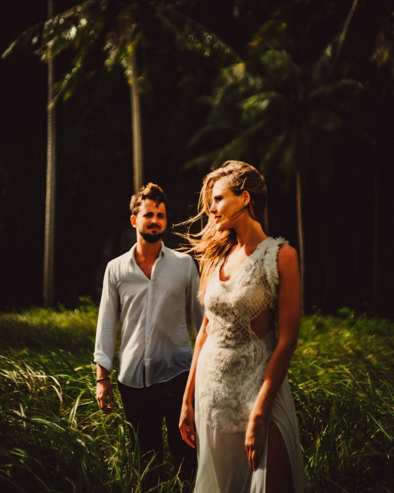 Moody couple portraits with a tropical vibe against a shadowy limestone cliff, palm trees and knee-high cogon grass, Pinagbuyutan Island, El Nido, Palawan, Philippines, Southeast Asia, December 2019, Sony A7III.