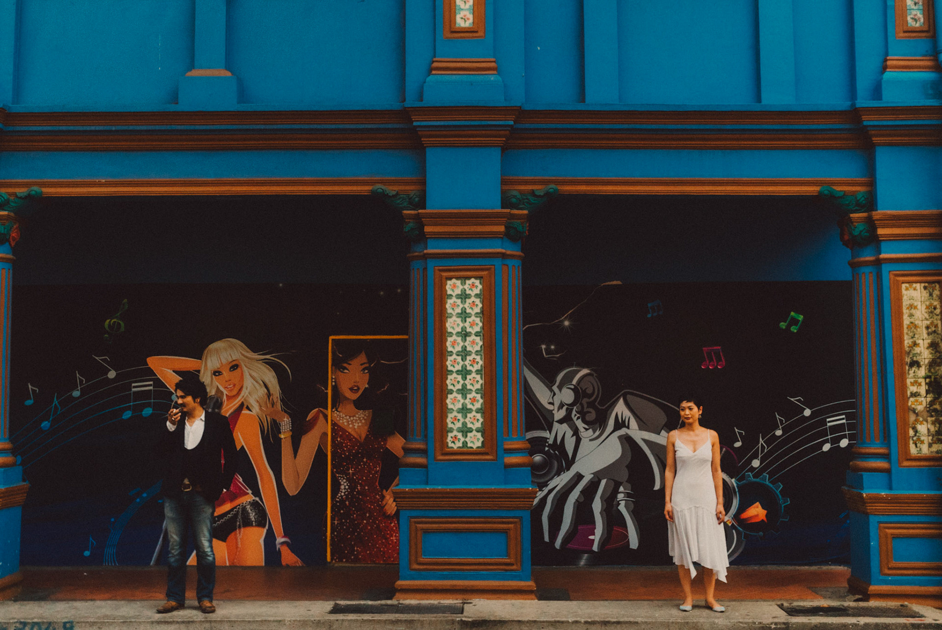 A Japanese couple standing in front of a brightly colored building, Little India, Singapore, October 2015, Sony A7S.