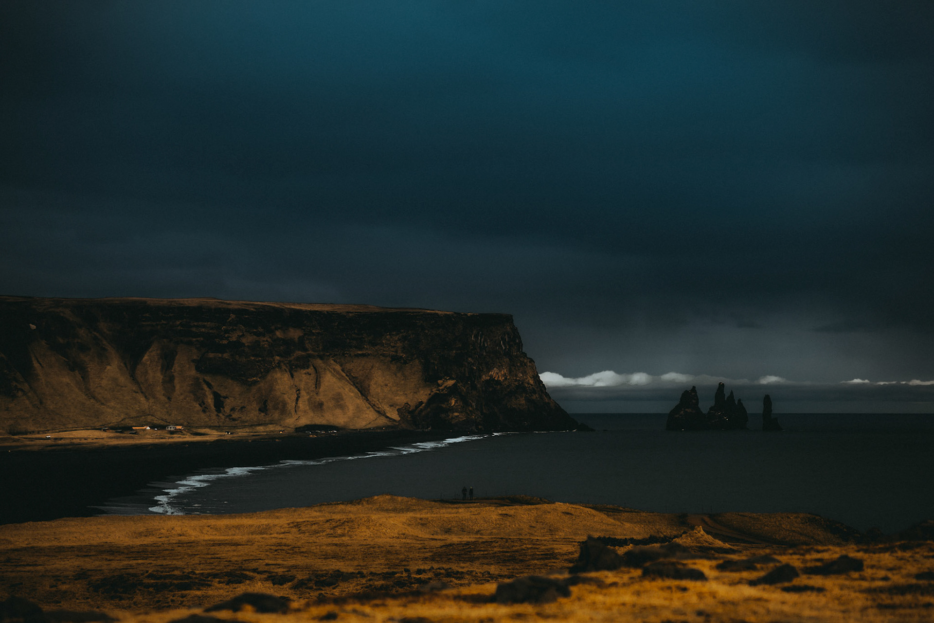 Tiny people in big places. A moody landscape photo of jagged cliffs and needle-like rock formations, as seen from Dyrhólaey Viewpoint, Iceland, May 2016, Sony A7RII.