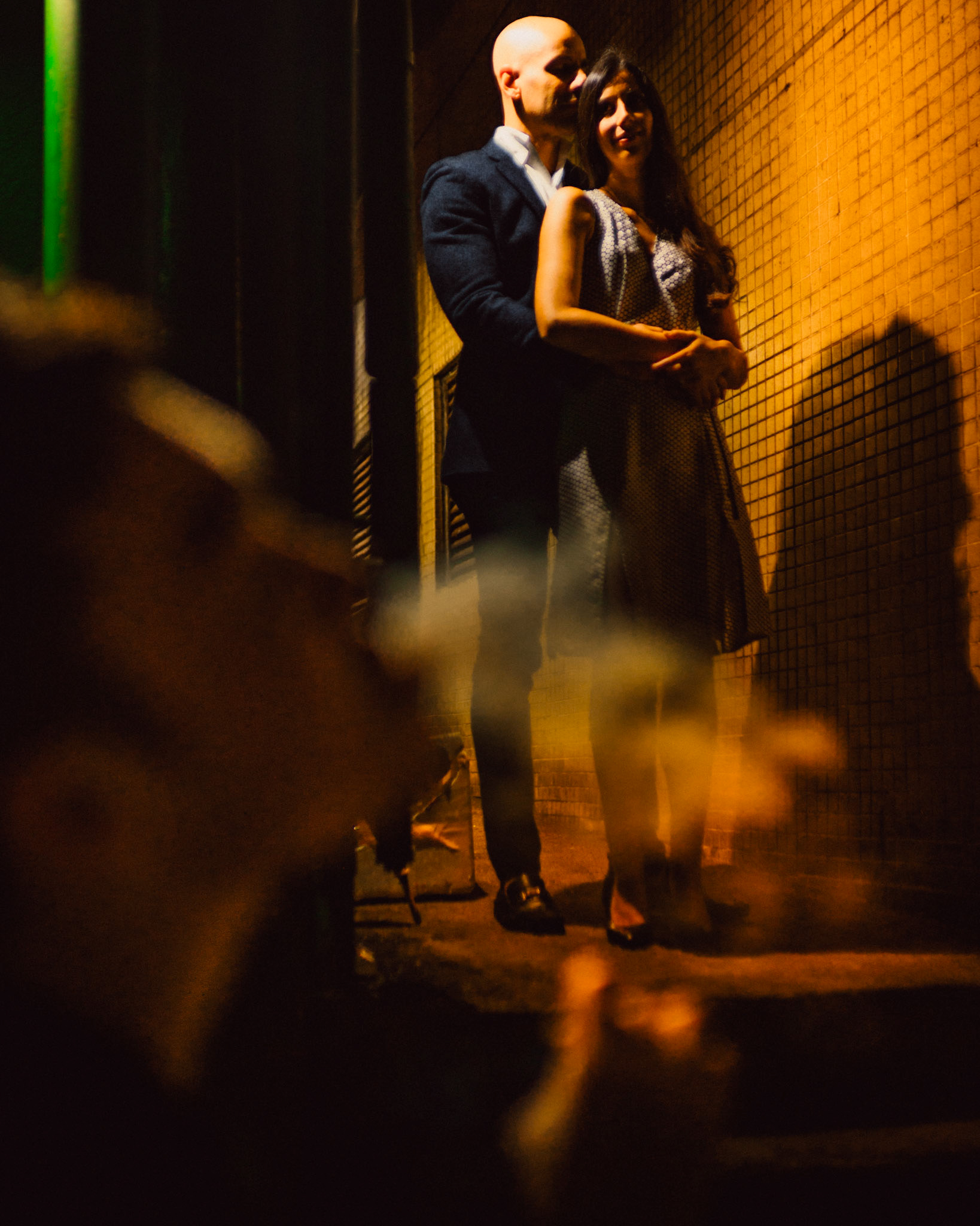 A moody and intimate late night urban engagement shoot with an incidental bystander blowing smoke in the foreground, from Eric and Sabrina's prewedding shoot in Central, Hong Kong, April 2019, Sony A7III.