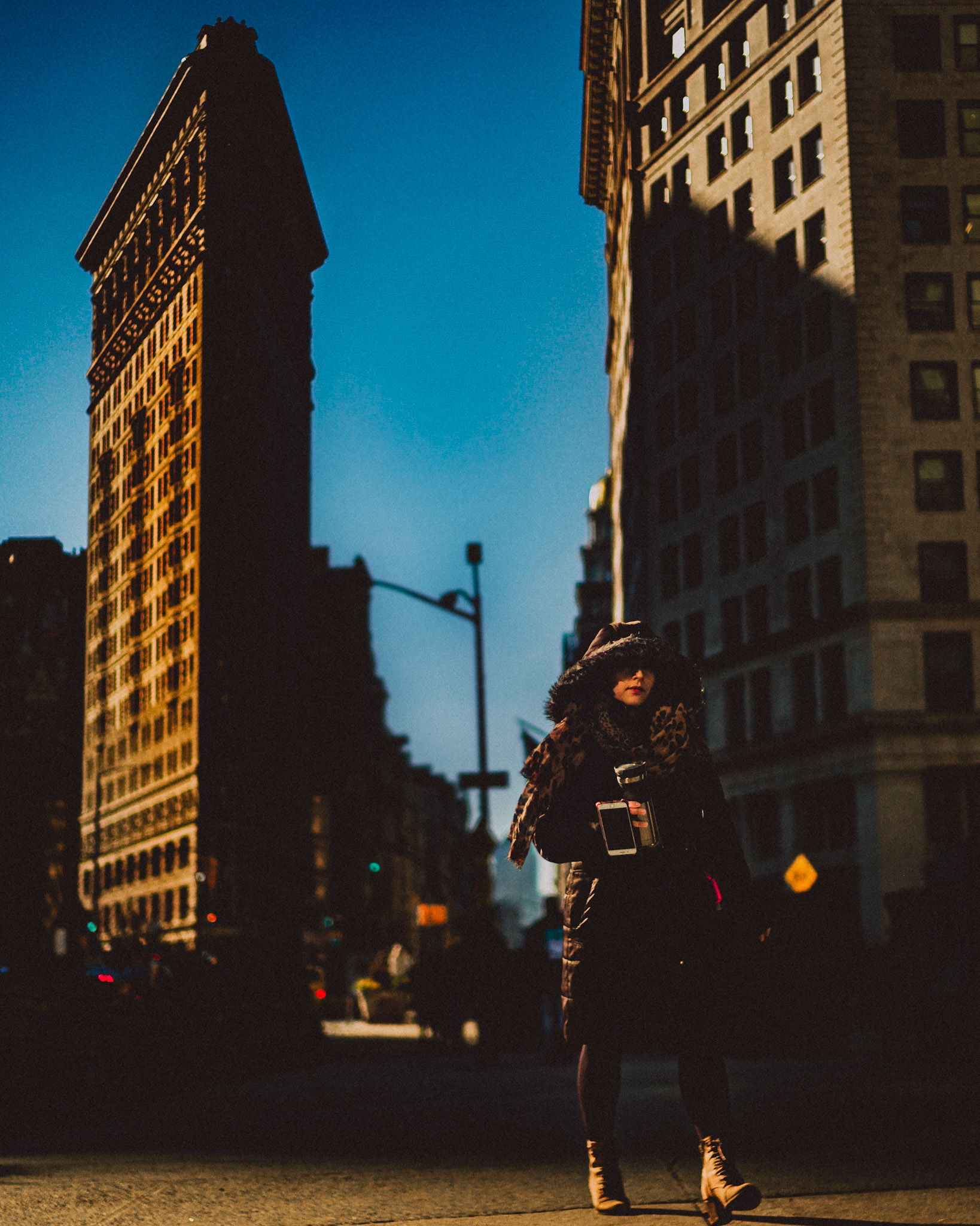 A candid photo of a stylishly dressed woman in front of the Flatiron Building, Manhattan, New York City, USA, December 2017, Leica M.