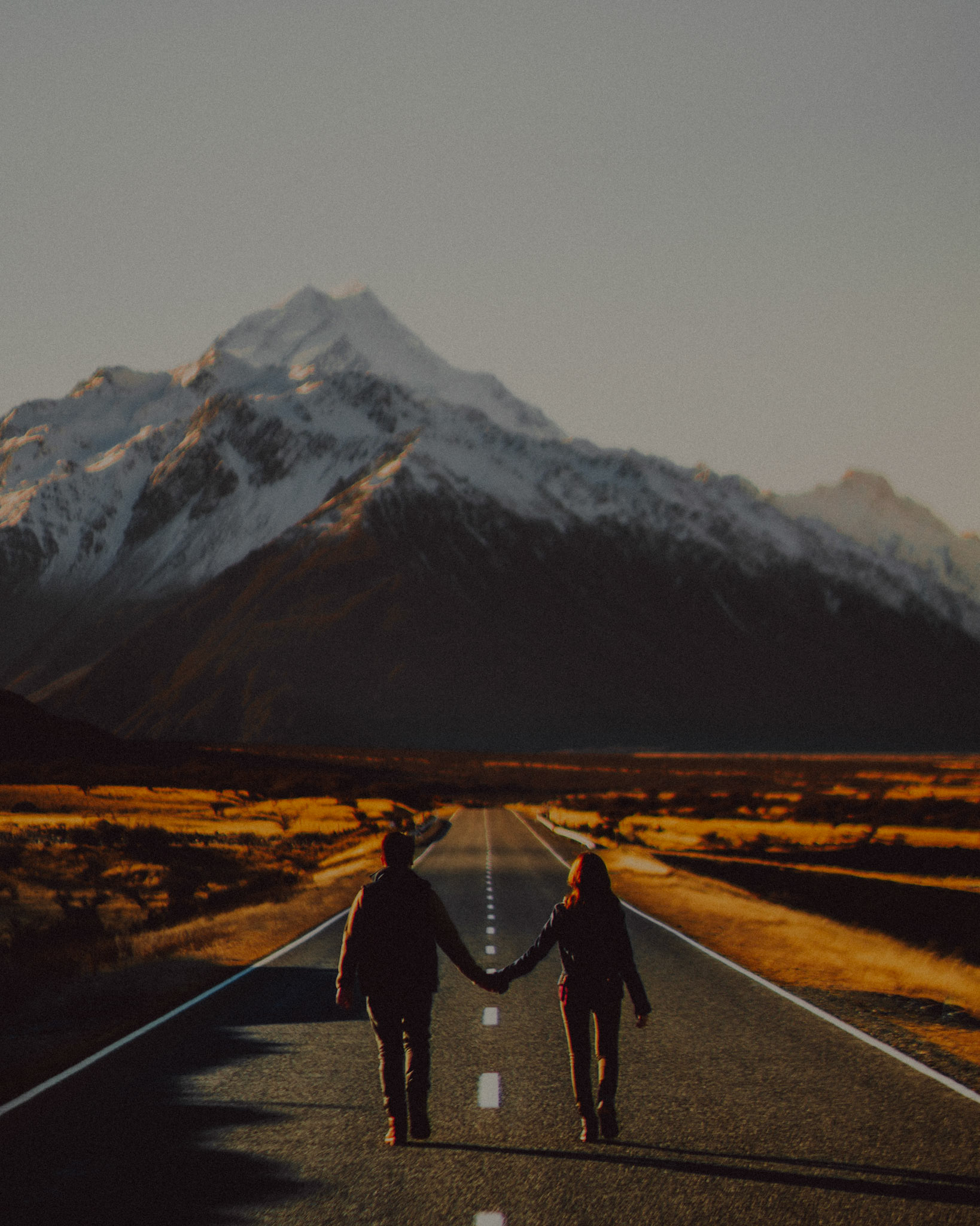 Couple adventure and travel portraits with Mount Cook's prominent snowy mountain peak and a lonely road, New Zealand, June 2017, Leica M.