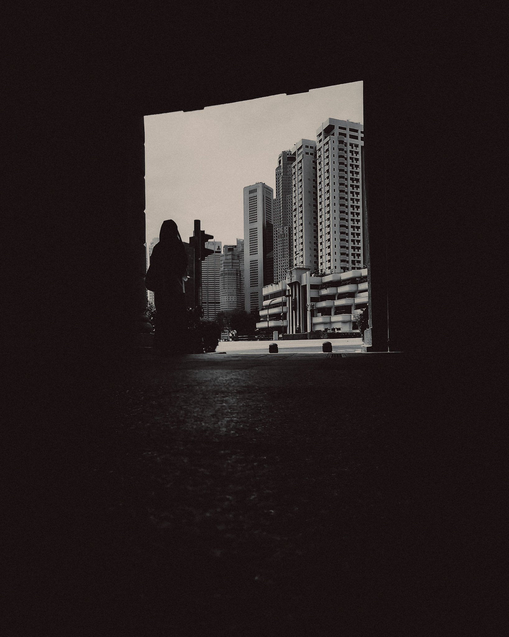 A black and white silhouette photo of a girl under an archway, about to cross the street, Boat Quay, Singapore, March 2019, Huawei Mate 20 Pro.