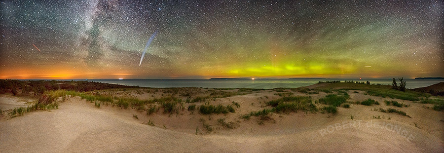 A Panorama of Sleeping Bear Point with the glow of northern lights and the milky way and a comet. Aurora Borealis