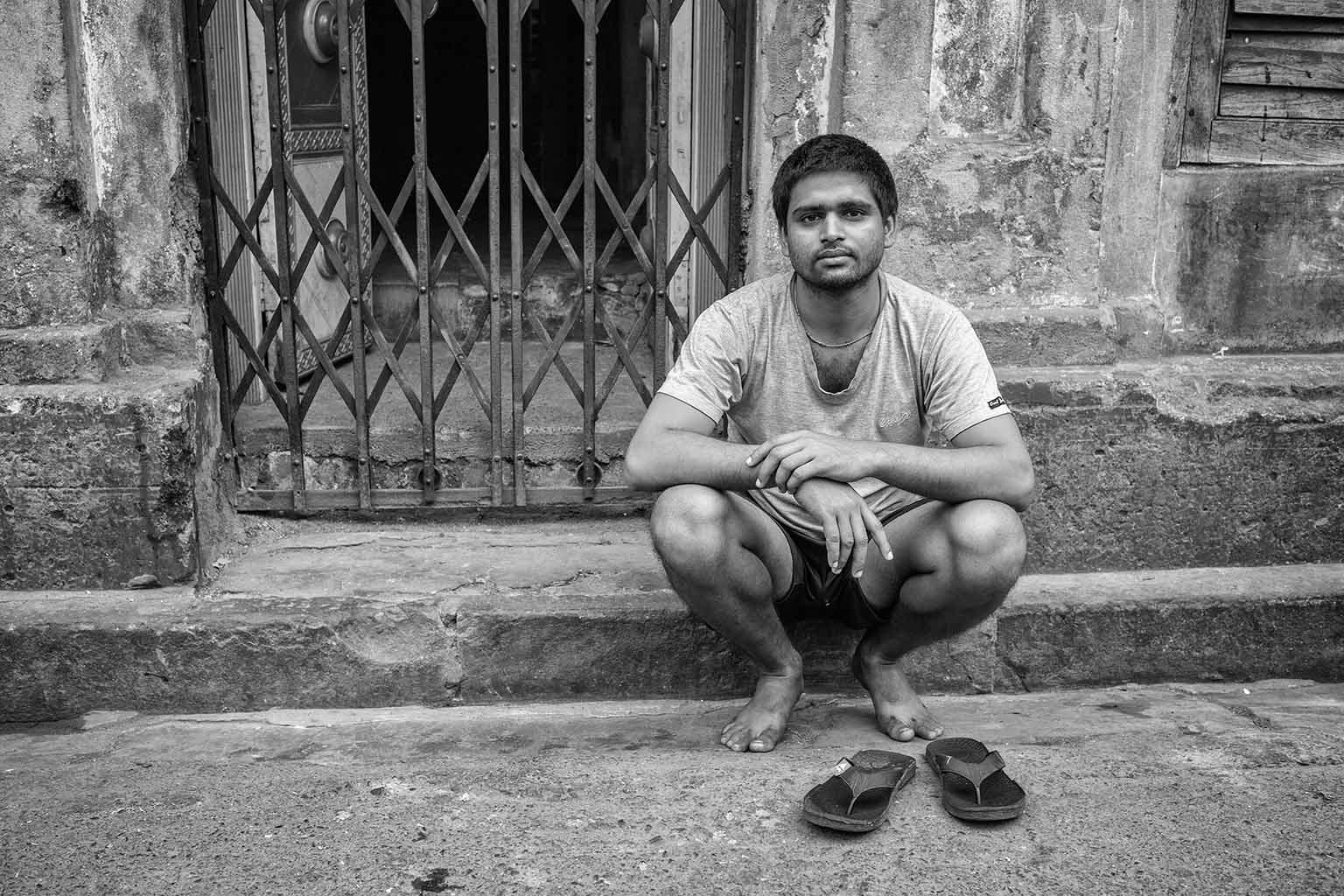 Portrait of a young man sitting on steps at the side of the road