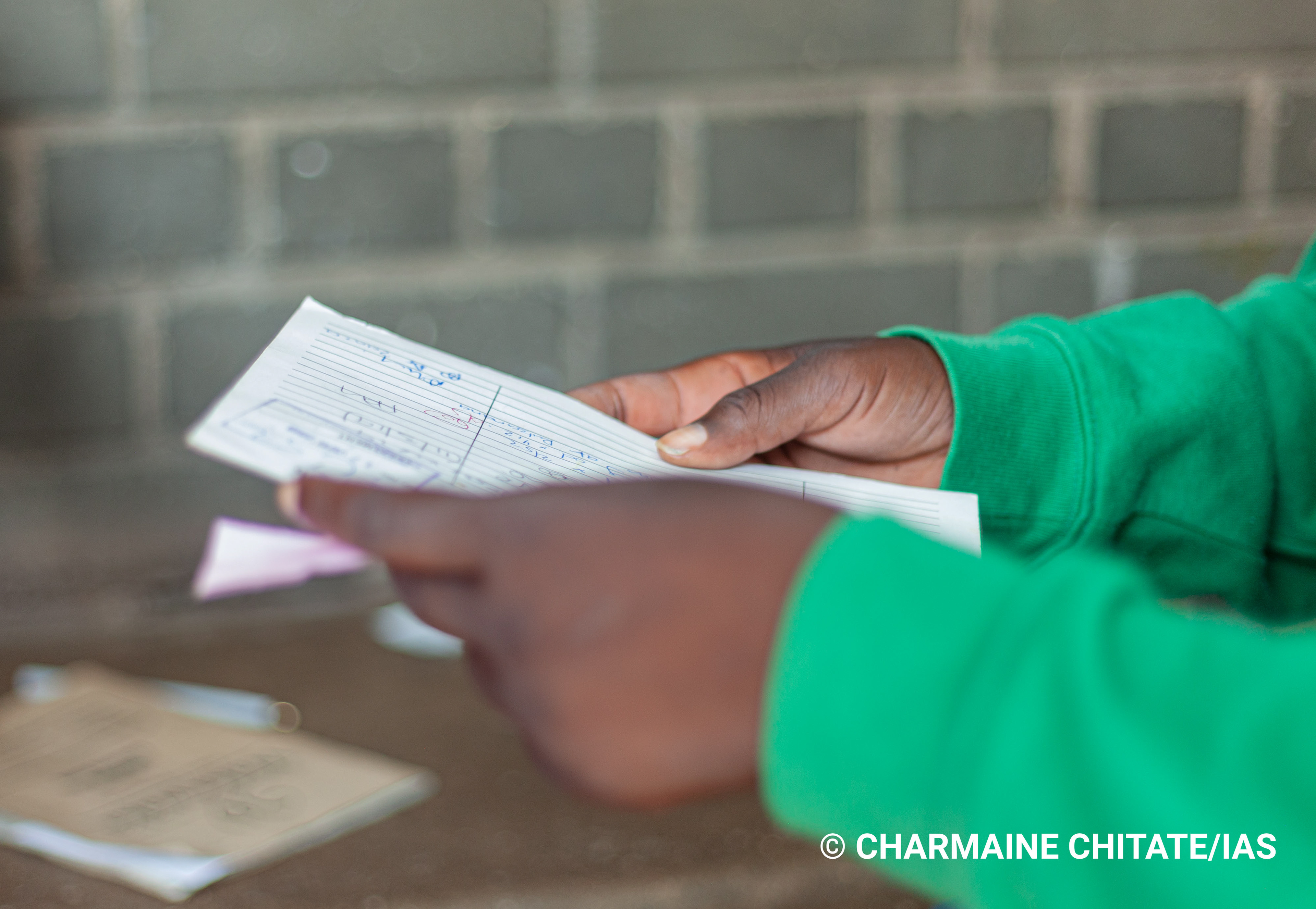 A TB patient holds their "white-card" which has become the reference term for TB/HIV patients in the community surrounding Rutsanana Polyclinic in Harare, Zimbabwe. (Photographer: Charmaine Chitate/IAS)