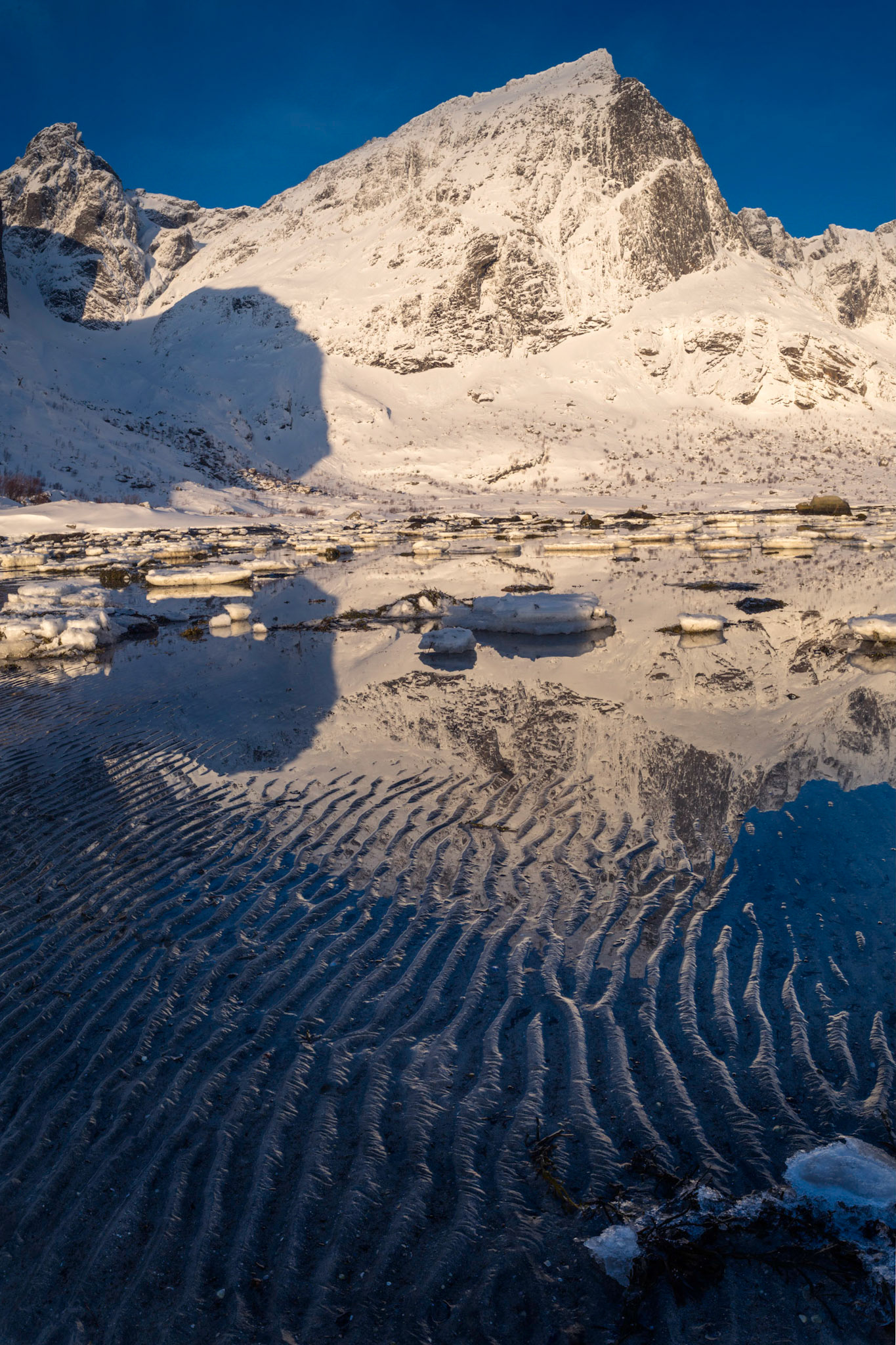 Stortinden, reflected in the tide pools of  Flakstadpollen.Flakstad, Nordland, NorwayMarch 22, 2018This is a panoramic images consisting of 3 frames stitched in Photoshop. Additional processing in Lightroom and Photoshop.PENTAX K-1, HD PENTAX-D FA 24-70mm F2.8ED SDM WRISO 100 24 mm  ¹⁄₄₀ sec at ƒ / 16