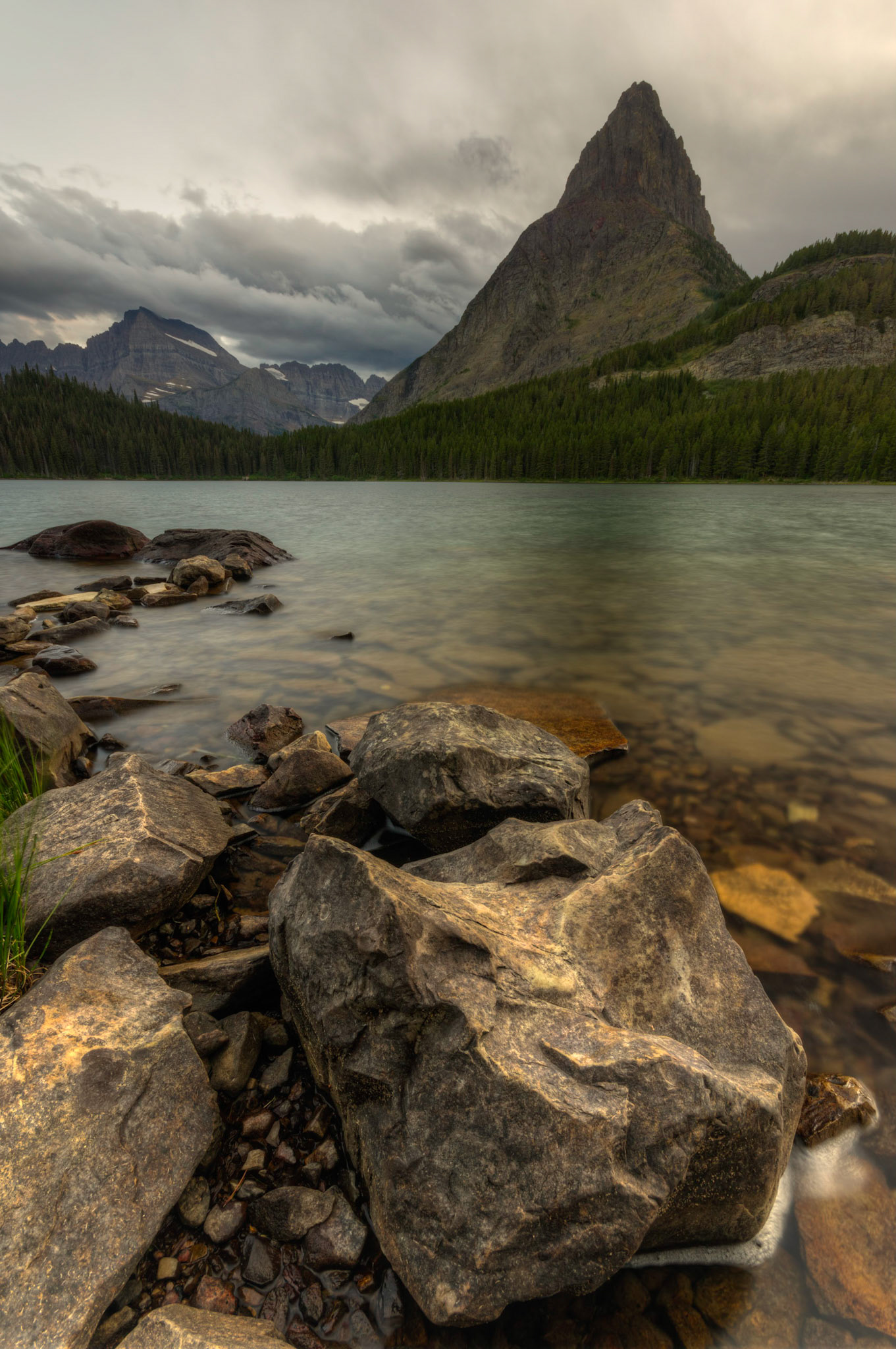 Swiftcurrent Lake, backed by Grinnell Point.  A very cloudy sunset.Glacier National ParkJuly 28, 2015This is an HDR image consisting of 5 exposures merged in Photomatix Pro. Additional processing in Lightroom and Photoshop.PENTAX K-3, Sigma 10-20mm f/4-5.6 EX DCISO 100 10 mm  4.0 sec at ƒ / 11