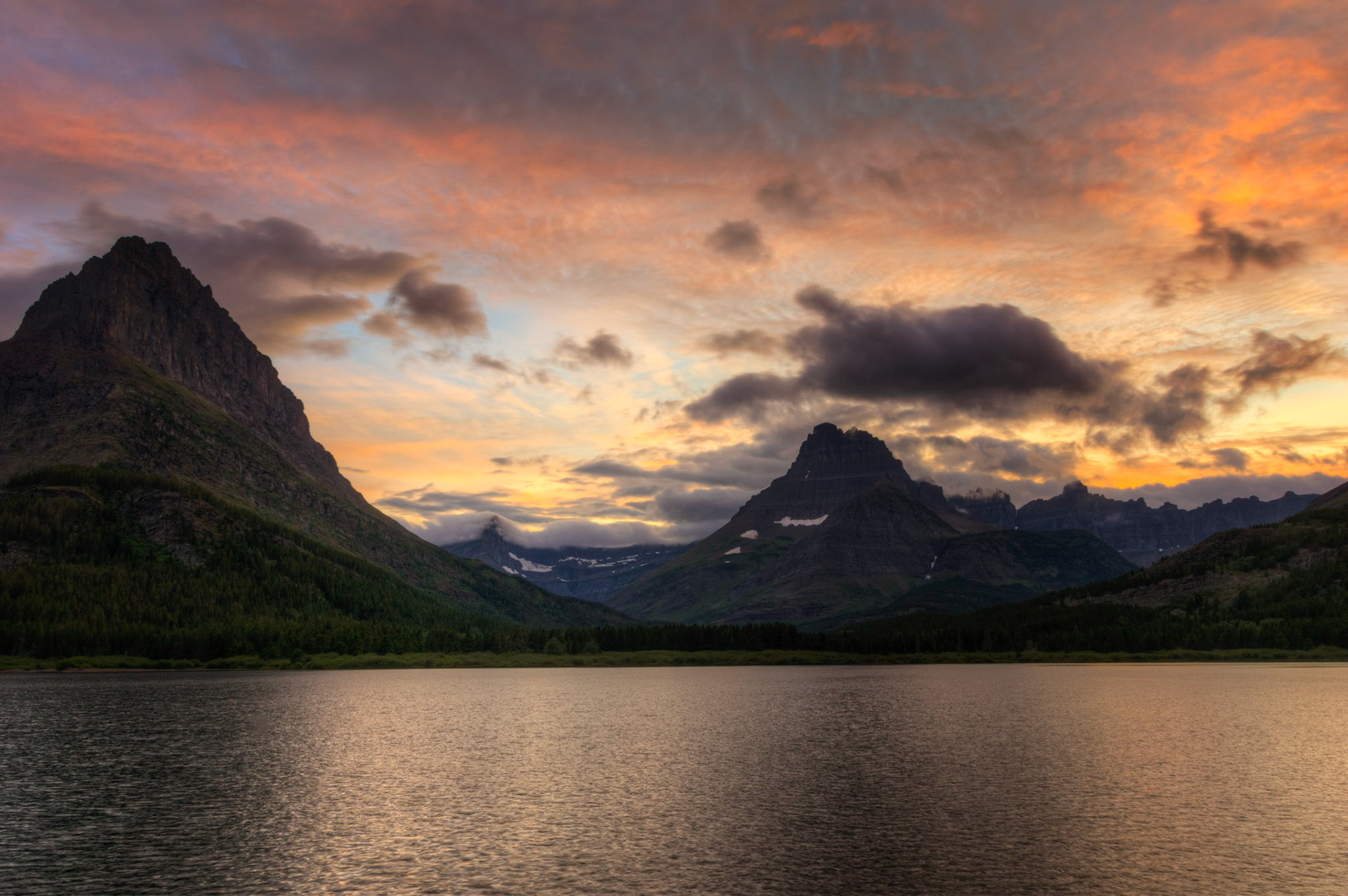 Sunset at Swiftcurrent Lake, with the backdrop of Grinnell Point, Mt. Wilbur, and the Ptarmigan Wall.Glacier National ParkJuly 27, 2015This is an HDR image consisting of 5 exposures merged in Photomatix Pro. Additional processing in Lightroom and Photoshop.PENTAX K-3, Sigma 18-250mm f/3.5-6.3 DC OS HSMISO 100 18 mm  ¹⁄₂₅ sec at ƒ / 11