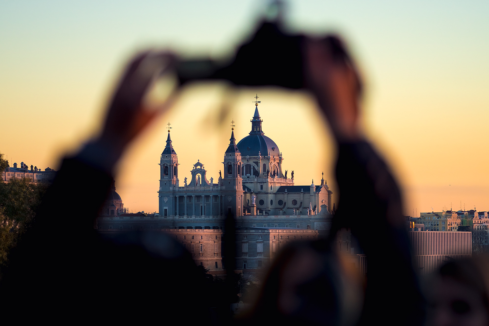 Catedral de la Almudena de Madrid al atardecer entre los brazos de un turista haciendo fotos ilustrando un artículo sobre el centro de interes en composición fotográfica