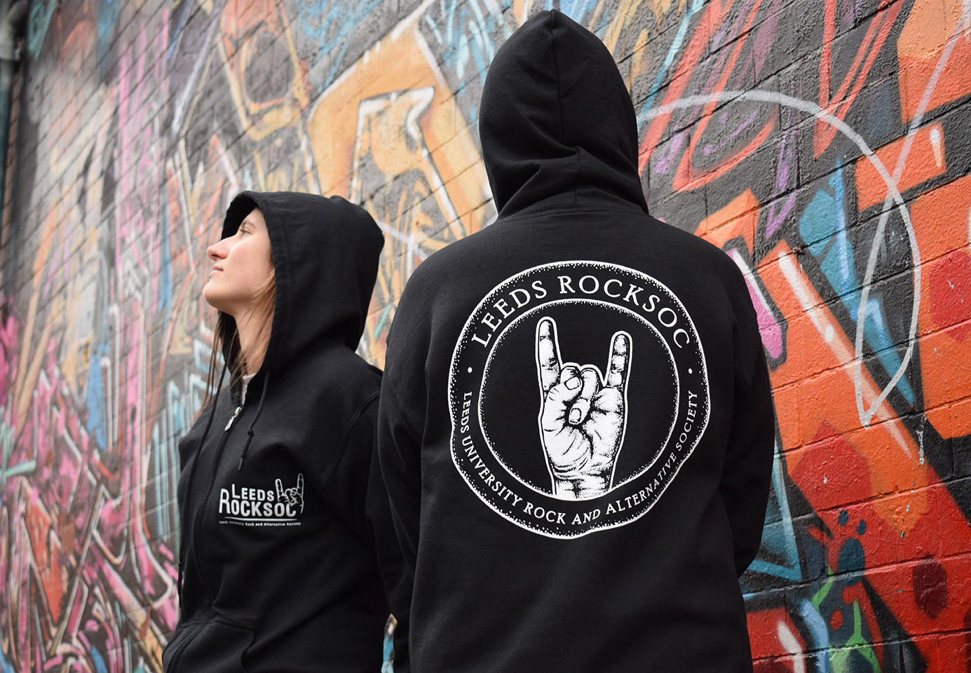 Two figures wearing black Rocksoc hoodies, with printed white dotwork logos =
