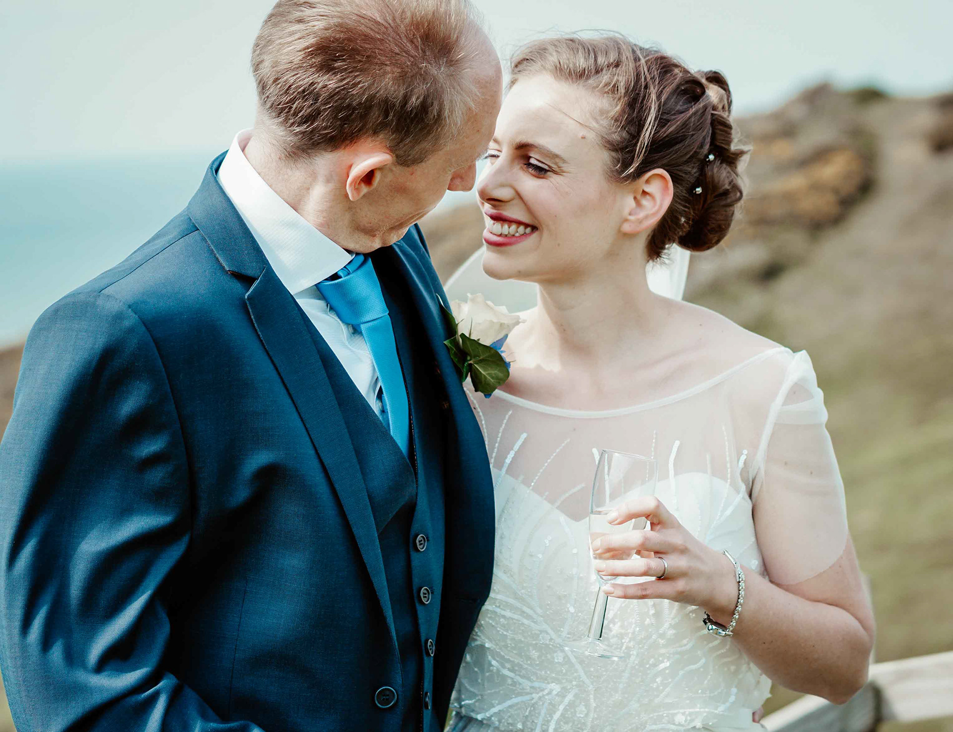 gorgeous young couple stood at balcony at ocean kave wedding venue on sunny windy day by the sea taken by david lefebvre
