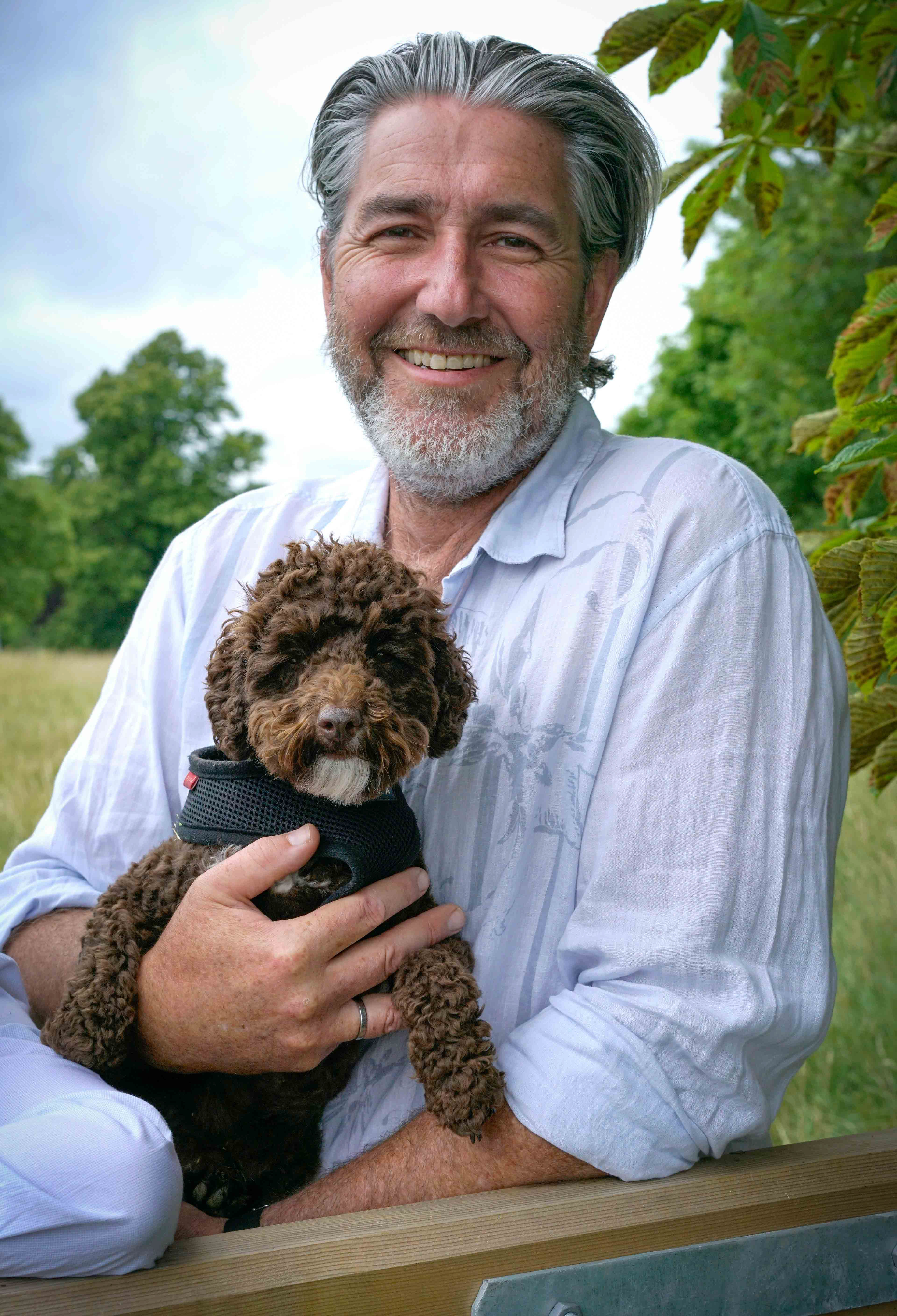 father smiling with dog in arms