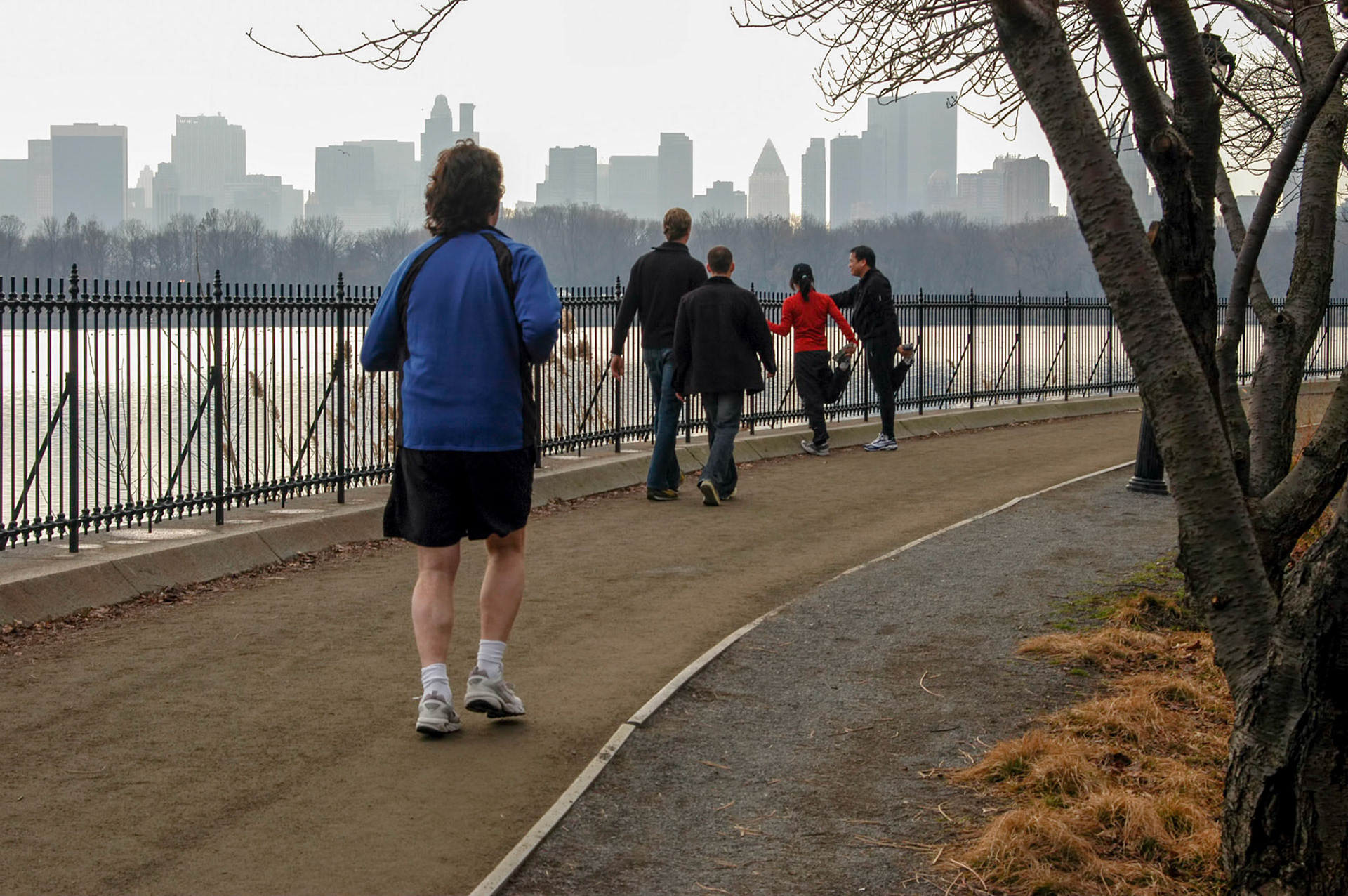 Joggers running and stretching along the resevoir in Central Park in New York City.