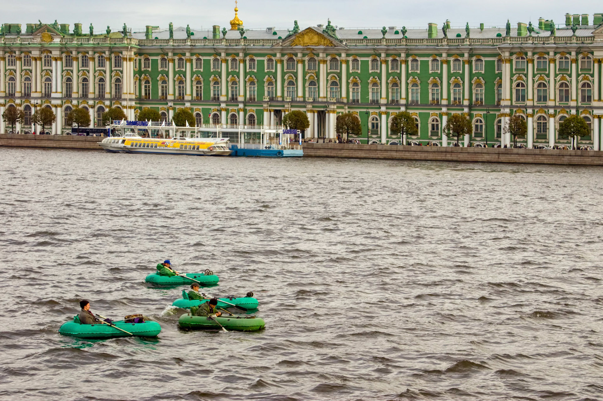 Some fishermen in inflatable rafts float on the Neva River near the Winter Palace in St. Petersburg Russia.