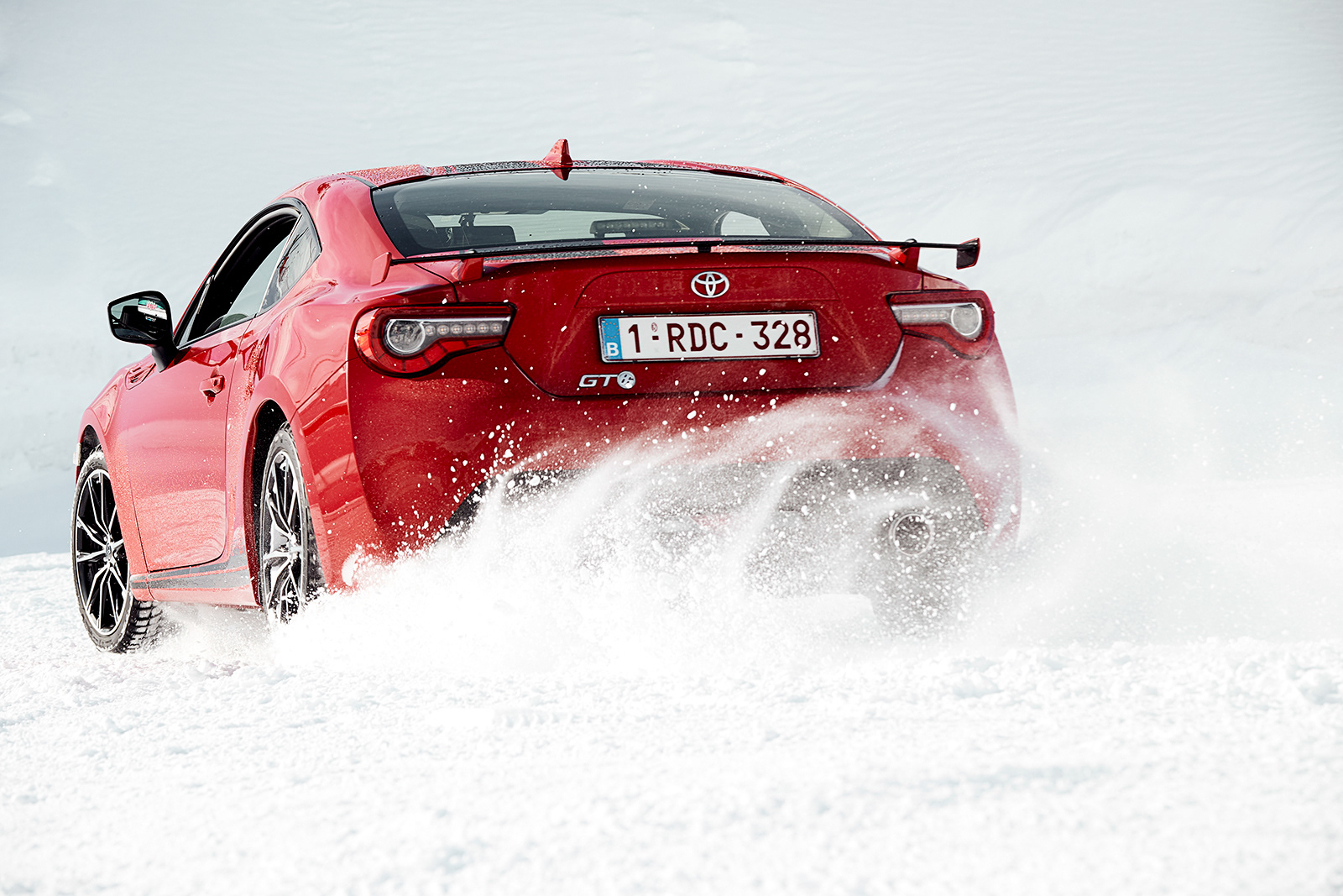 back of drifting sports car with snow flying