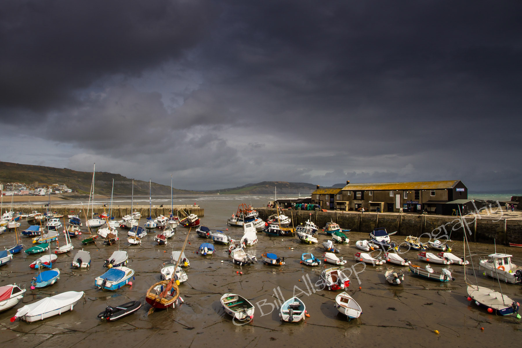 Lyme Regis harbour at low tide on a stormy day.