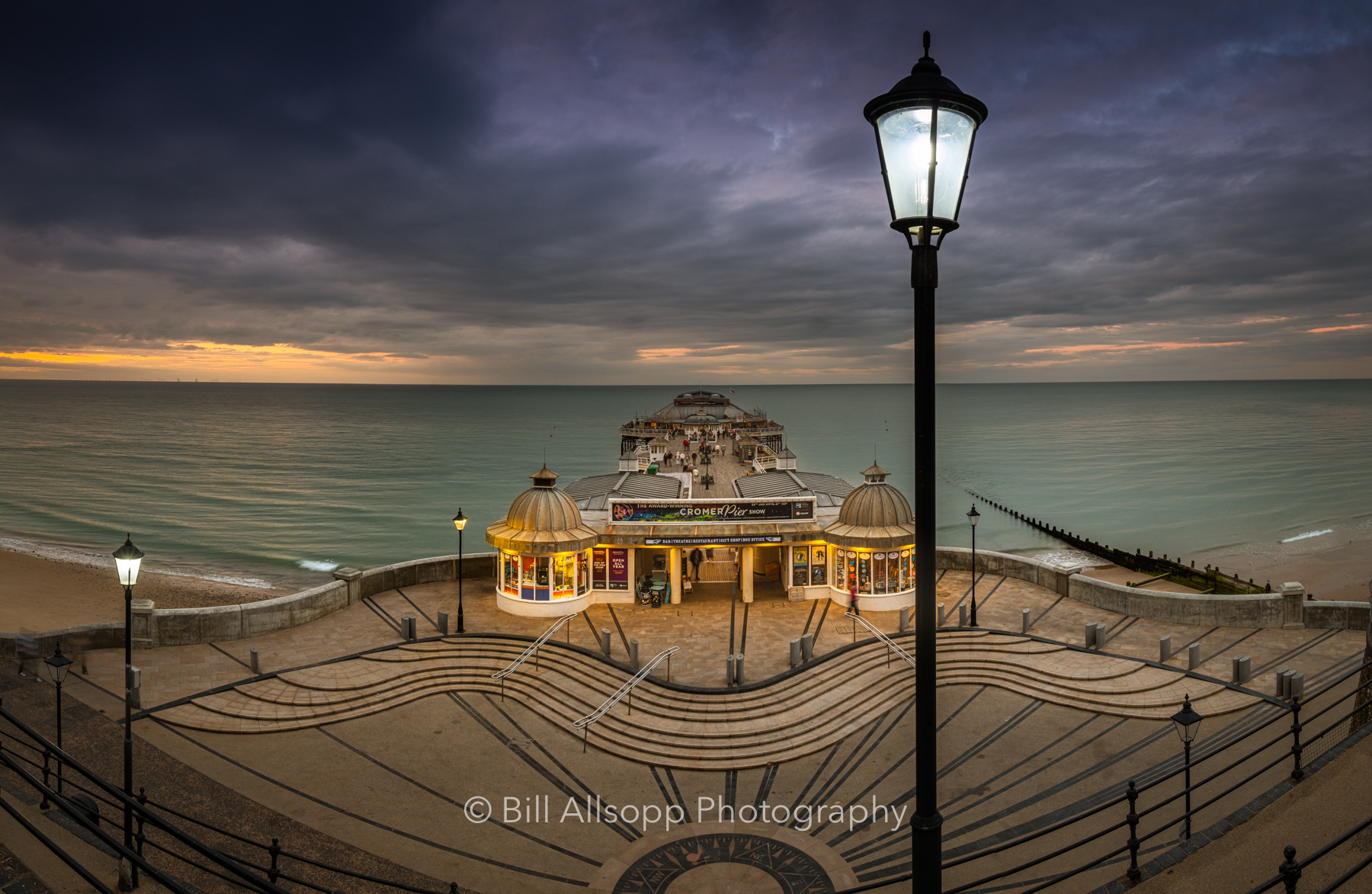 The street lights start to come on as the sun sets at Cromer pier.
