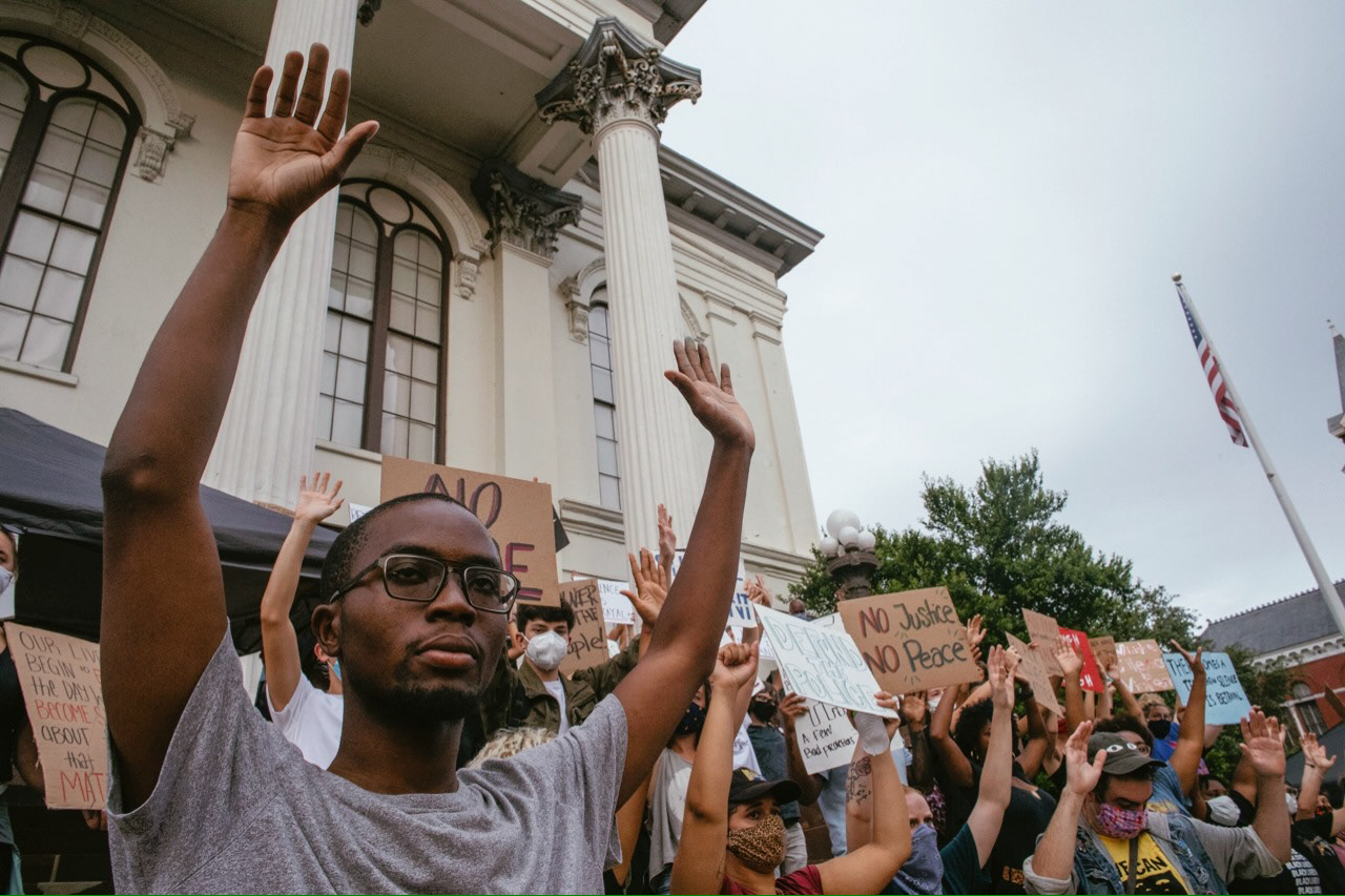 Maurice Wilson, along with the rest of the crowd, holds his hands up to show understanding of the struggles the black community faces. This demonstration, officially called a "block party," took place in front of the courthouse in downtown Wilmington.