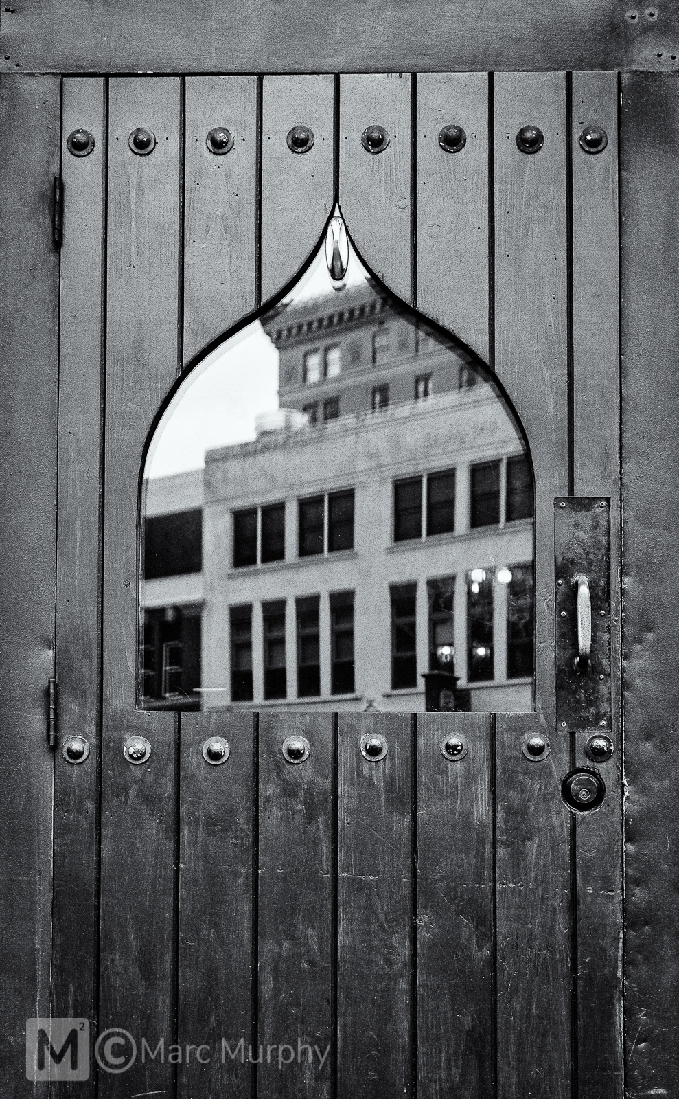 Black and White Unique Shaped Window in Old Wooden Door with Reflections of Downtown Asheville North Carolina