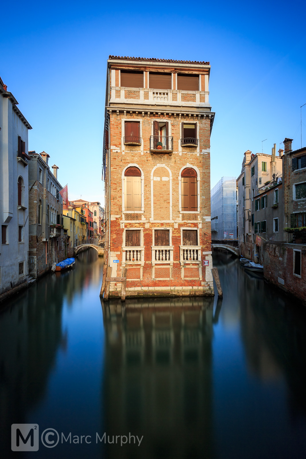 Building Splitting a Canal in the Castello Area of Venice Italy at Sunset with Smooth Water and Blue Sky