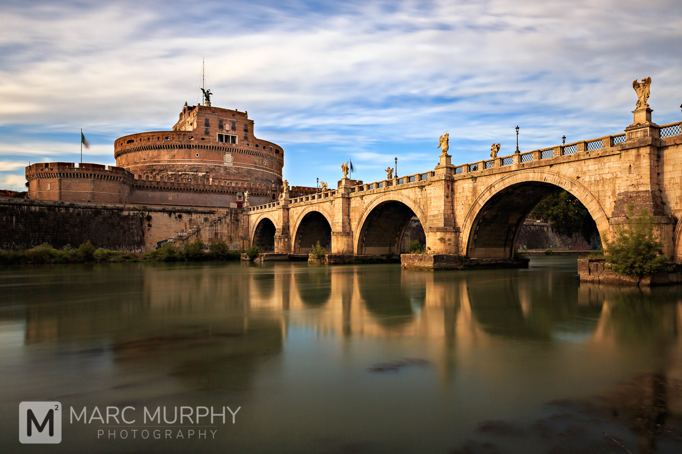 St. Angelo Bridge and Castel Sant'Angelo at Sunset with the River Tiber, Moving Clouds and Blue Sky in Rome Italy