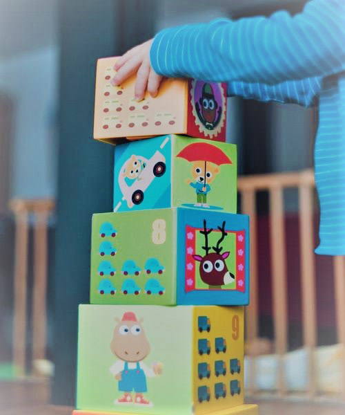 criança formando uma torre com quatro cubos empilhados