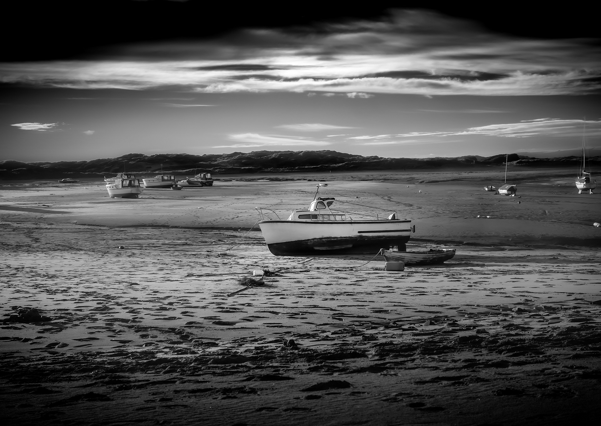 Boats lying on the dry sand waiting for the tide to come back in. Black and White photograph