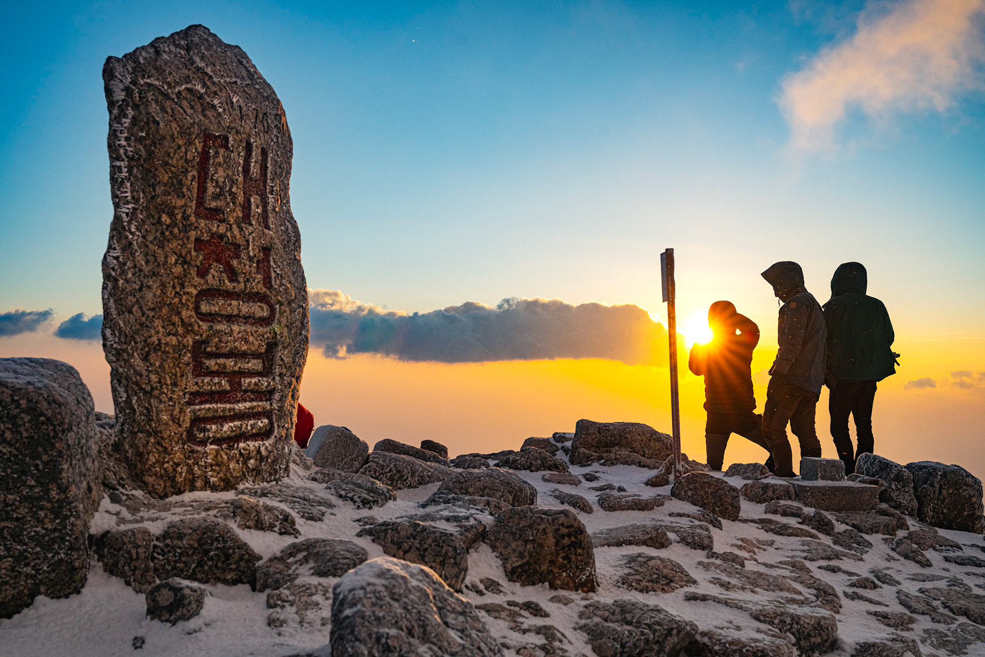 Seoraksan National Park, South Korea - FEB 03 2020: Hikers and Mountaineers congratulate eachother for braving gusts over 70kmph and windchill temperatures below -40 degrees C/F, and enjoy the reward of a beautiful sunrise. Hiking to the summit of high moutains to see the sunrise is a long standing tradition of Korean hikers and climbers. In winter, the challenge is much greater, but that does stop the most dedicated from pursuing their passion for hiking.