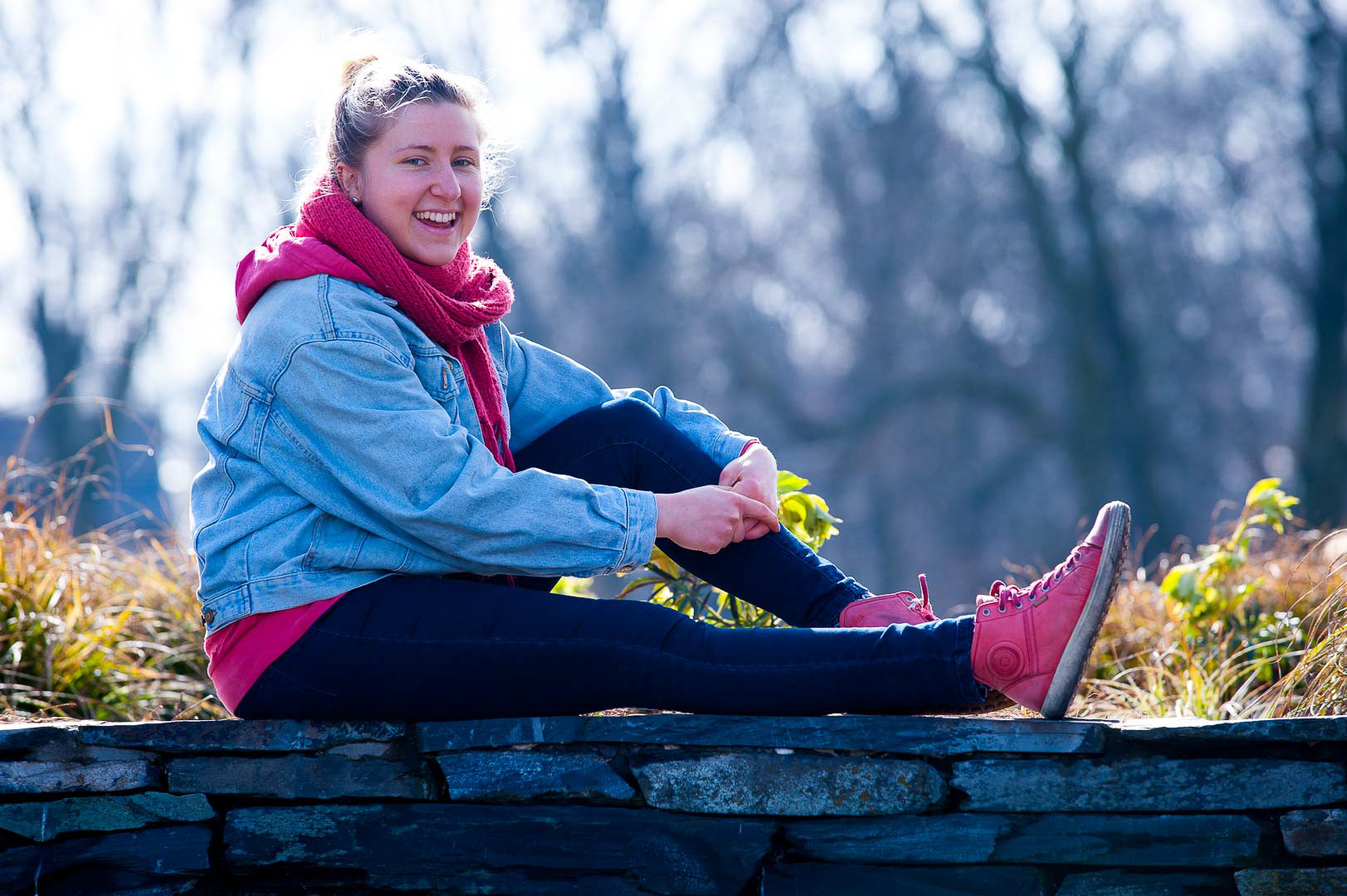 Lächelnde Frau sitzt auf Mauer im Treptower Park in Berlin