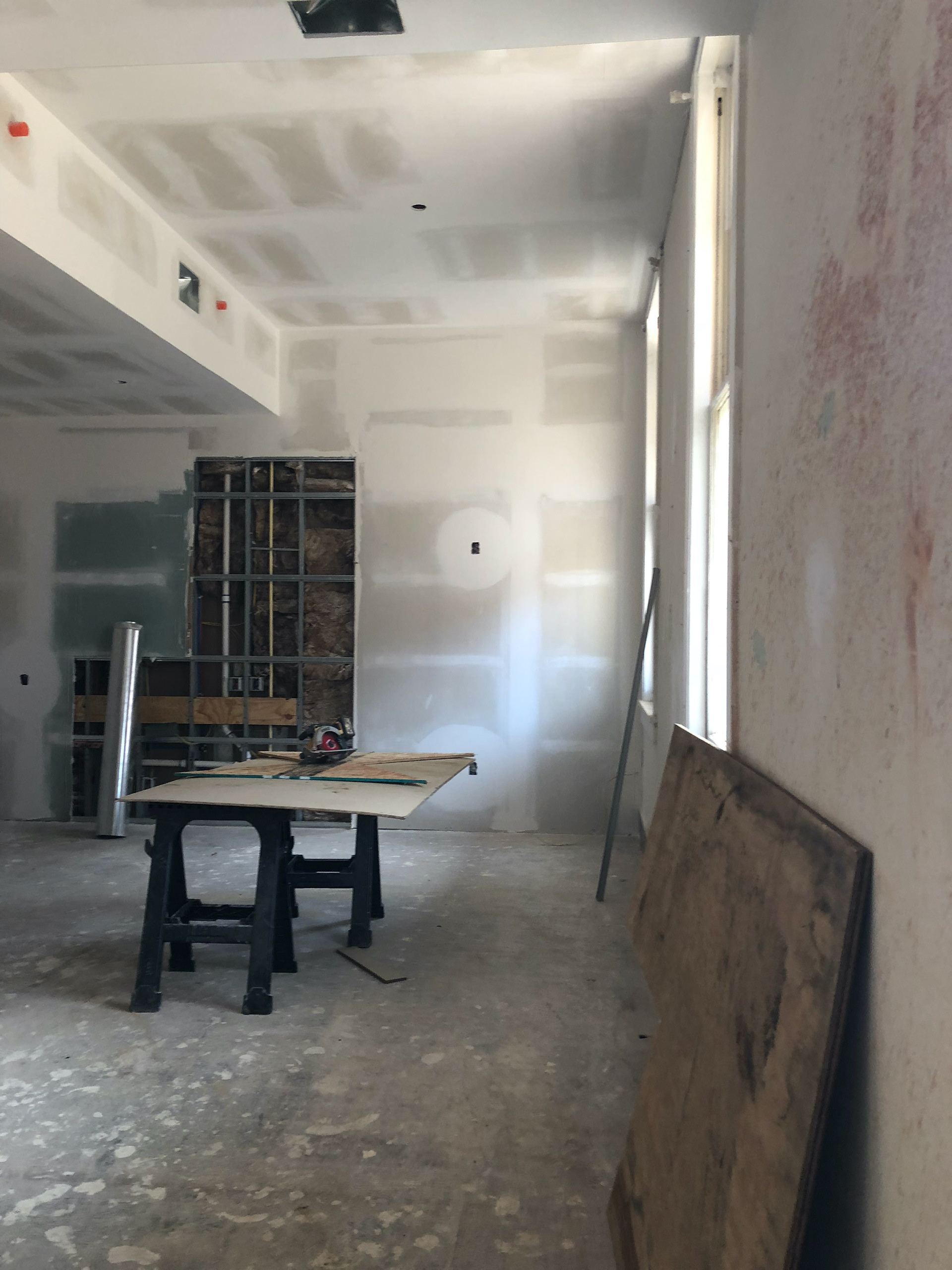 Apartment interior during construction, showing the high ceiling and natural light of the living room areas.