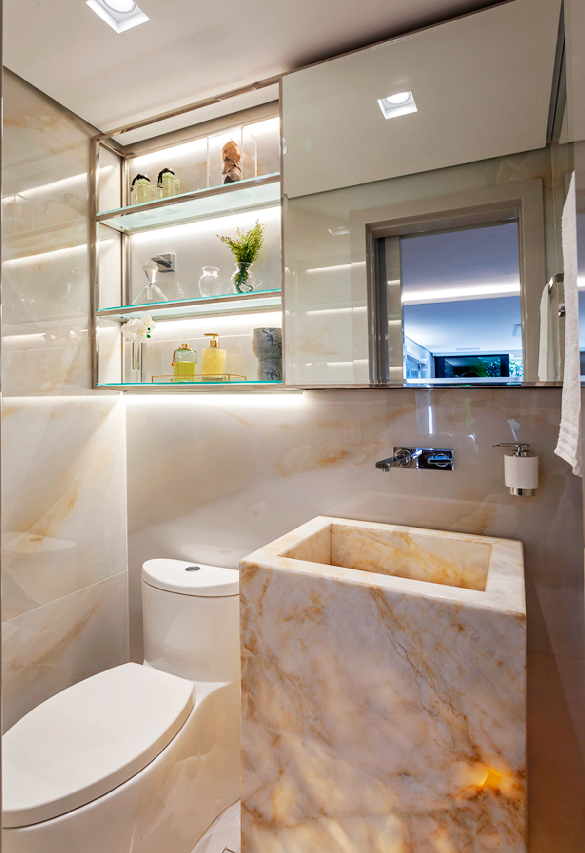 O lavabo é parte integrante da sala. A cuba esculpida, em mármore onix iluminado