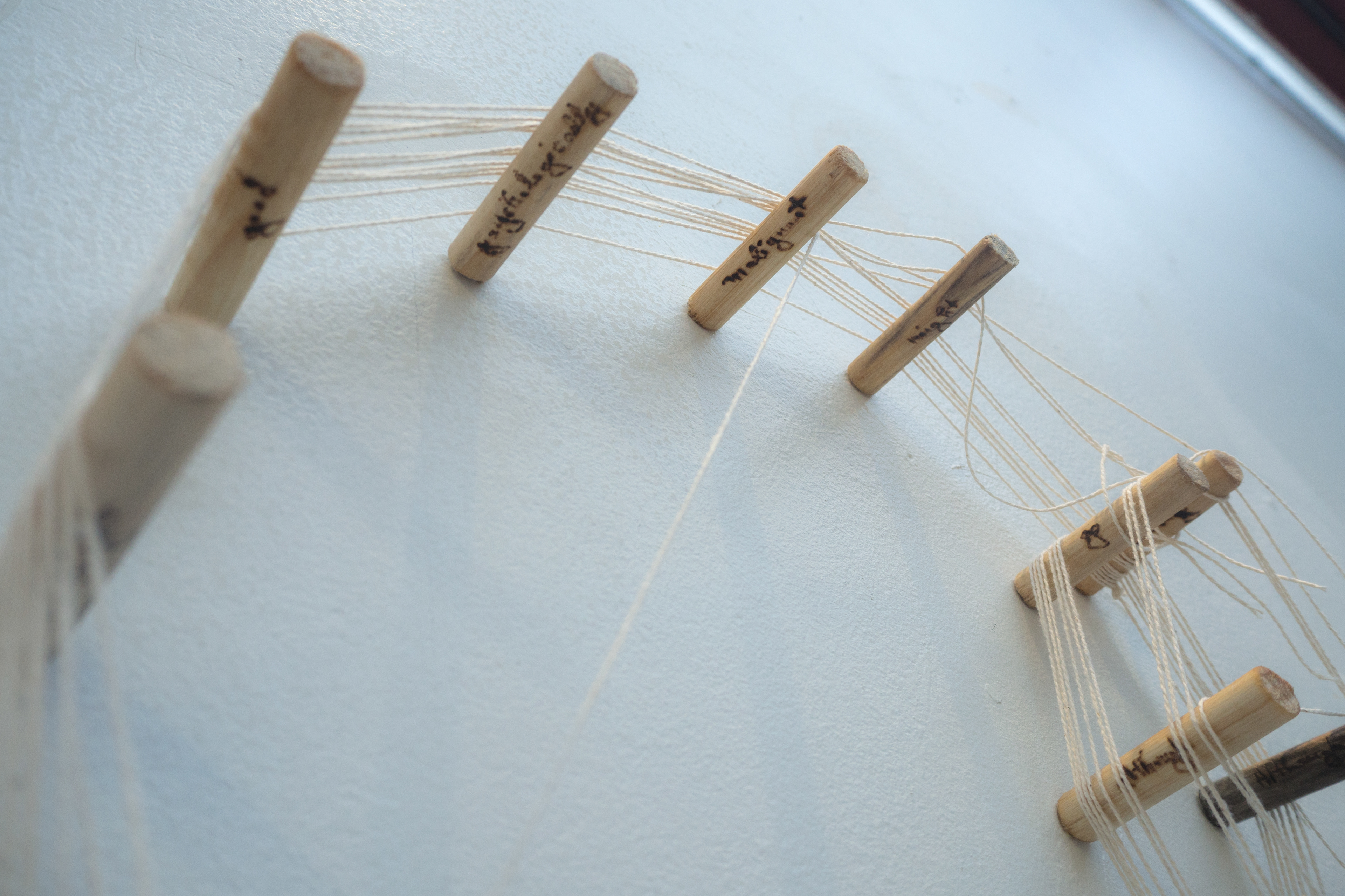 Words have been burned into the wooden dowels: "good," "psychologically," "malignant," "night," etc.