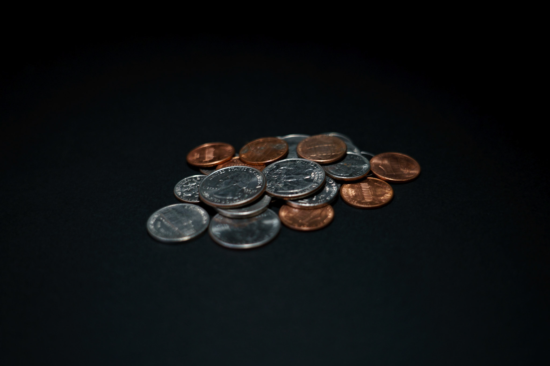 Painted Light: Low Key Image: Coins on black paper, 20201107, MILLER, Utilizing the black backdrop and a dark room with a snuted light, i was able to only pool light onto the coins while I operated the camera in bulb mode Camera Settings: Sony A7II, ISO 200, 48mm, f4., 1/10s