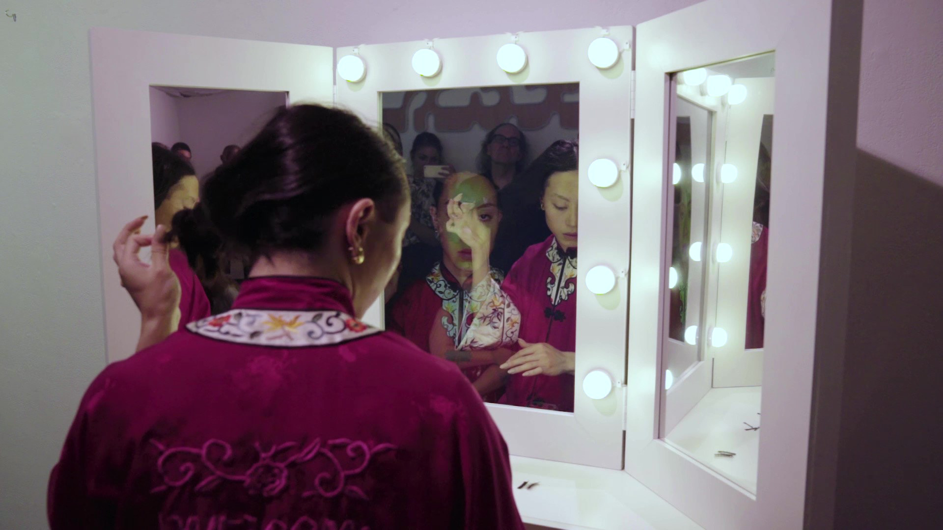 A person sitting in front of a vanity mirror wearing a robe