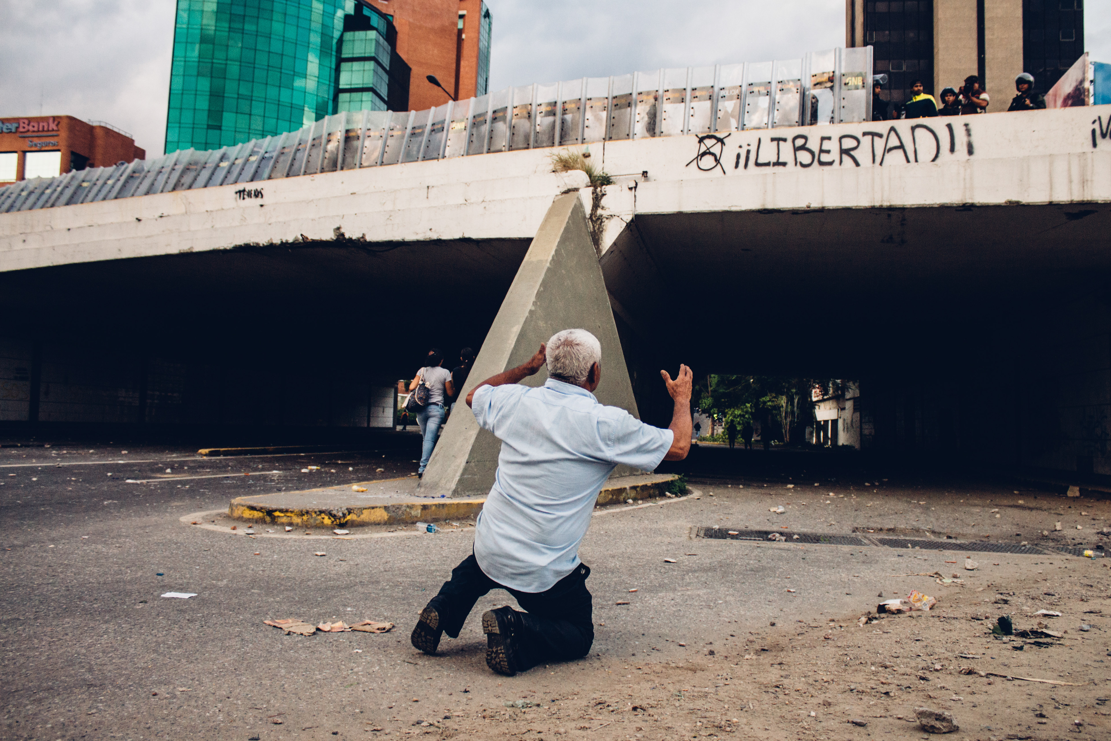 An old man kneels asking the National guards to take him instead of the protesters. Caracas 2014