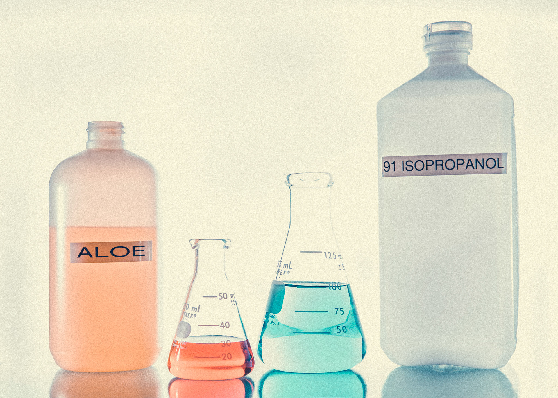 Homemade hand sanitizer using aloe and isopropanol measured in flasks.