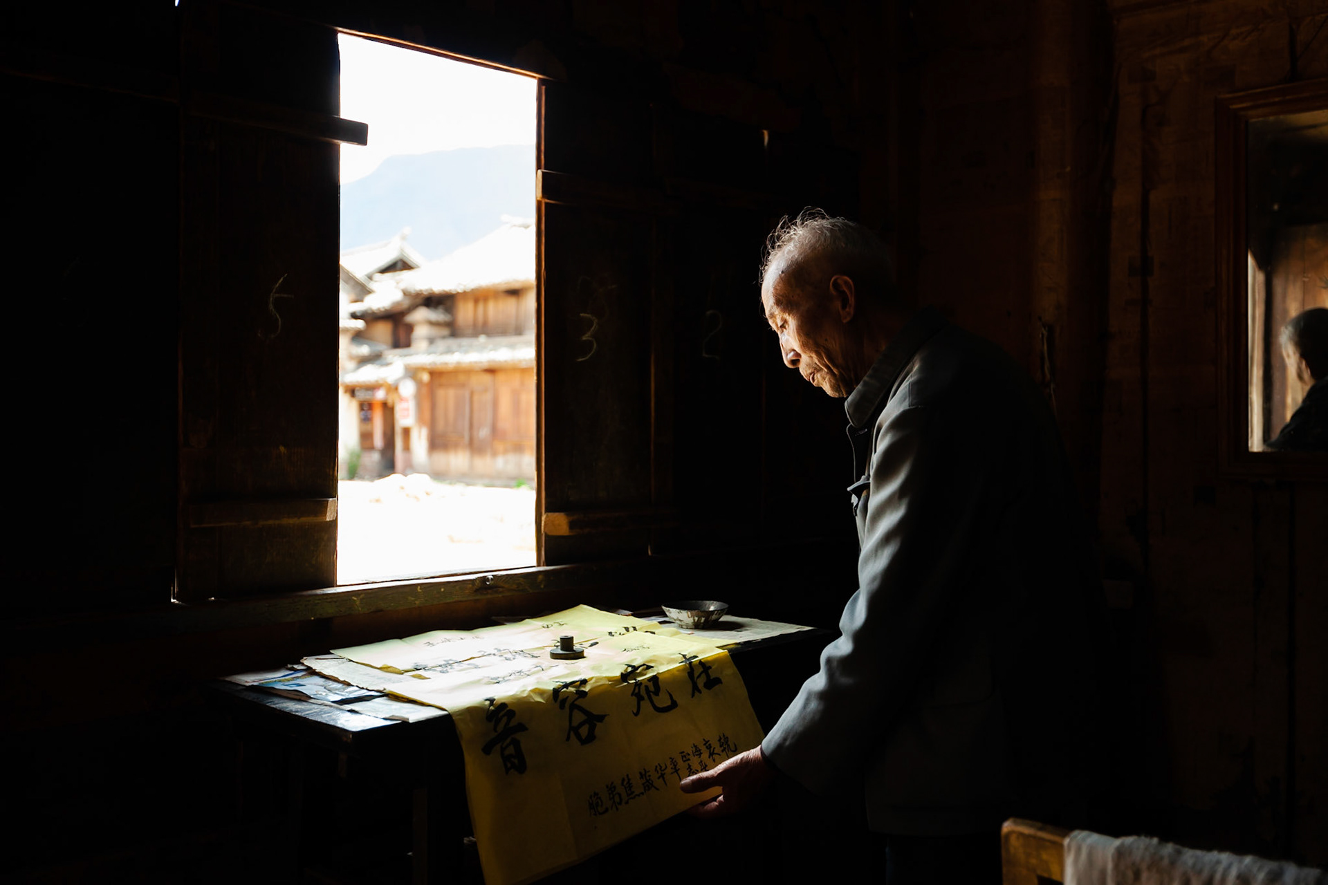 A Chinese Calligrapher making signs using traditional calligraphy in his shop in Shaxi, Yunnan Province, China.