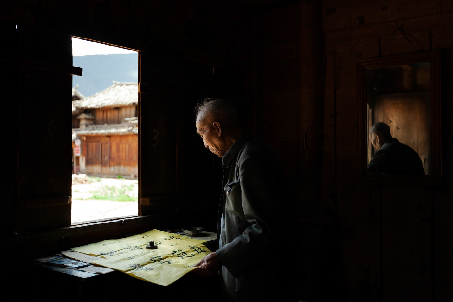 A Chinese Calligrapher making signs using traditional calligraphy in his shop in Shaxi, Yunnan Province, China.