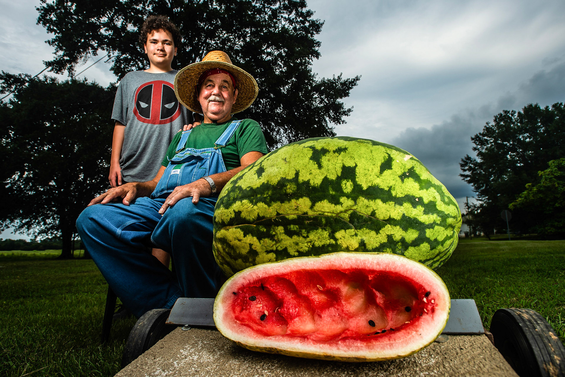 John W. Haggard, right, sits with his grandson, Walt Crisler, 12, for a portrait next to the watermelon, measuring at 60 inches in circumference, Haggard grew on Aug. 9, 2019, in Trinity, Ala. "I just plant and God sends the rain," said Haggard.