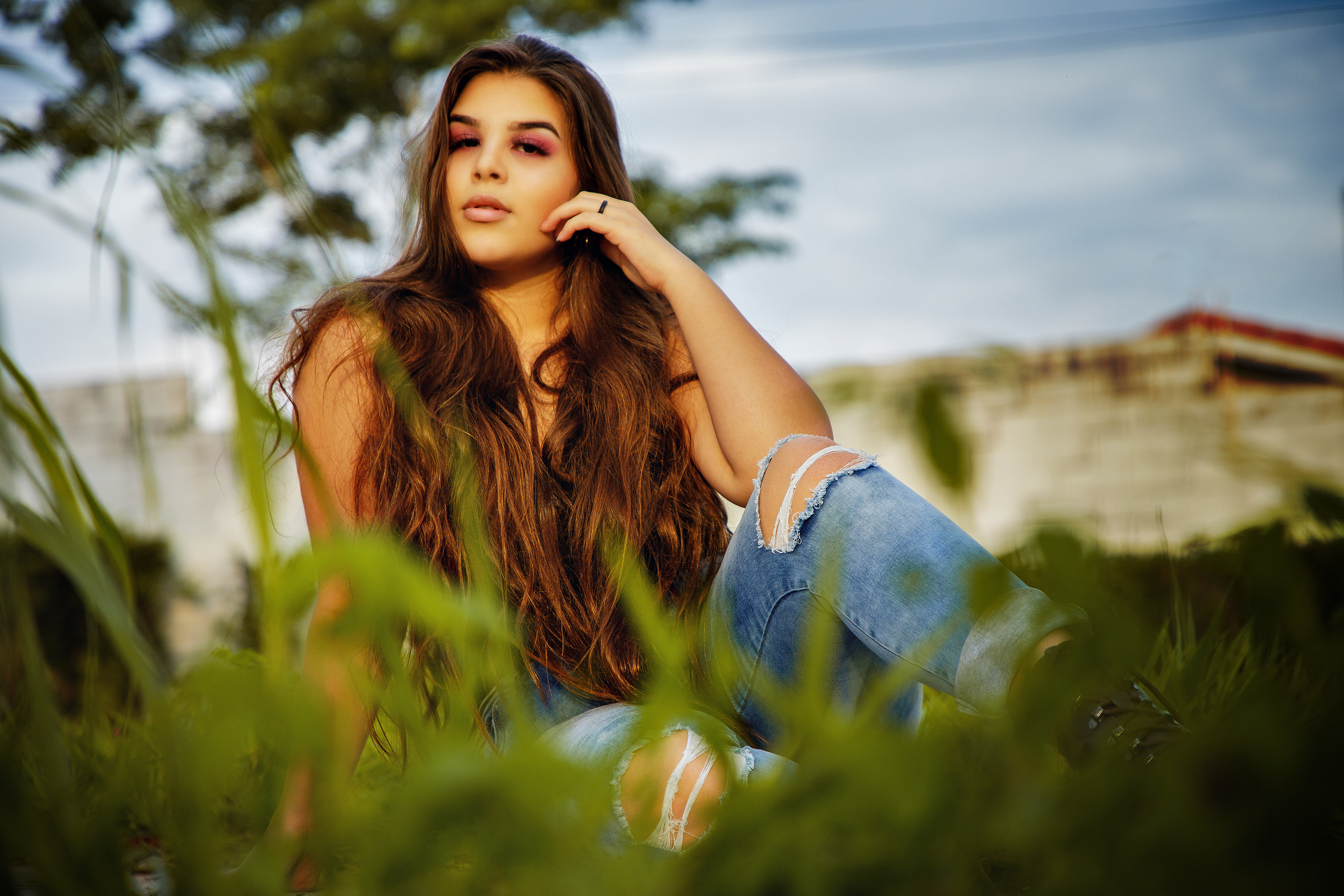 fotografia , retrato feminino campinas , esta foto tem uma garotoa de 15 anos sentada no chão com umas plantas a sua frente esta com olhar bem meigo a maõ no queixo e olhando para camera