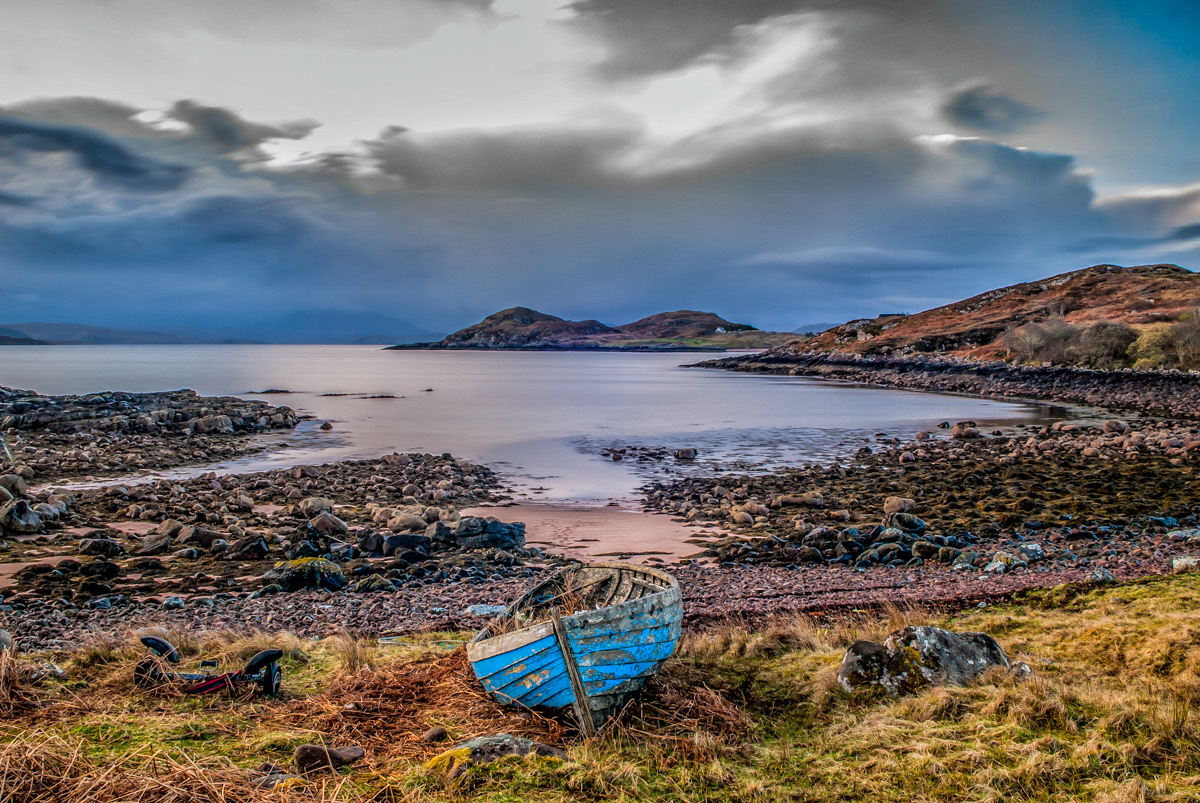 Blue rotten boat in-front of Scottish coastal highlands