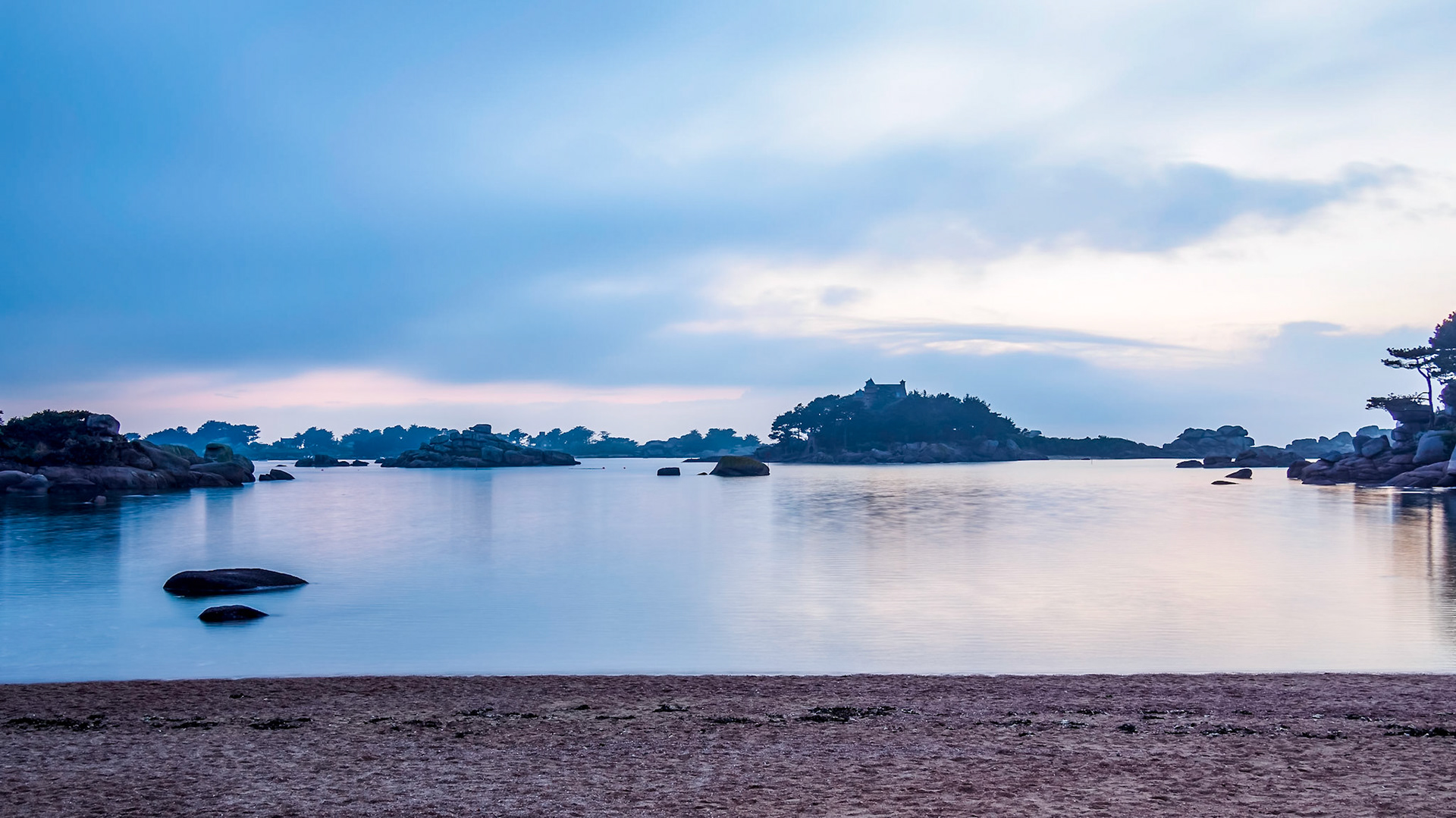 The bay of Saint-Guirec, France at blue hour in this long exposure shot, the water icy flat and calm.