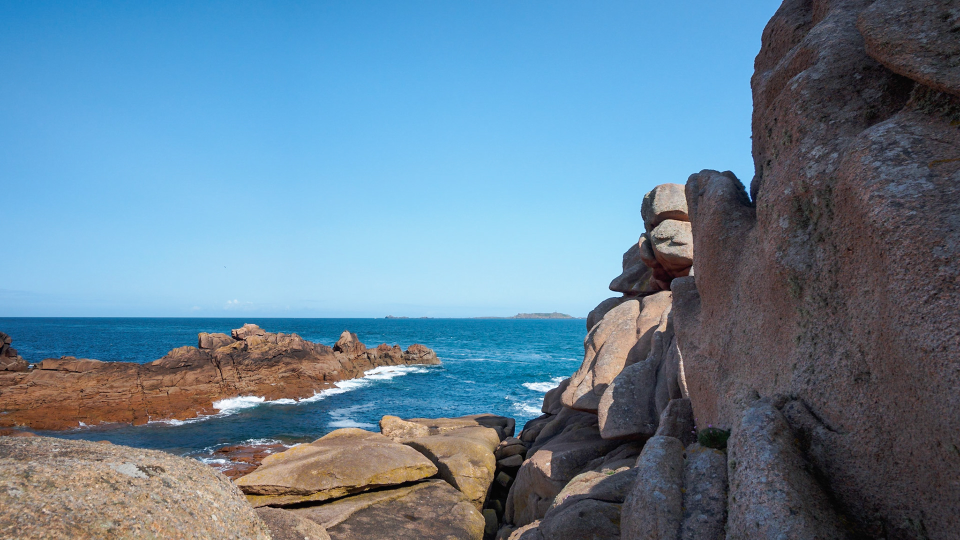 50 shades of pink, from pale rose to dark brownish, the pink granite coastline of Brittany in France. In the background, 3 of the famous seven islands: Ile Aux Moines, Ile Plate, and Le Cerf.