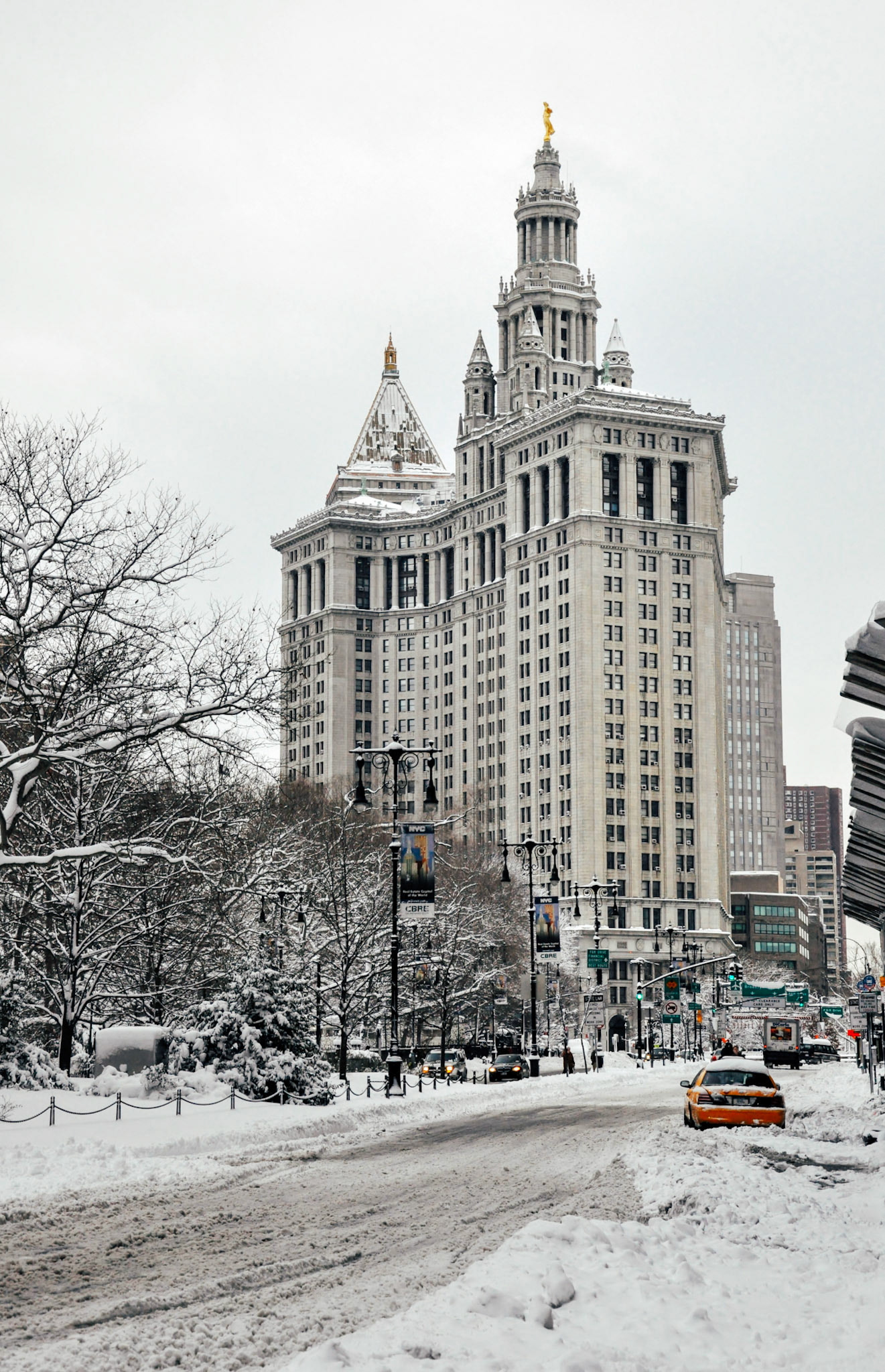 A classic Crown Victoria taxi cab is stuck in the snow in front of City Hall Park and the Manhattan Municipal Building.