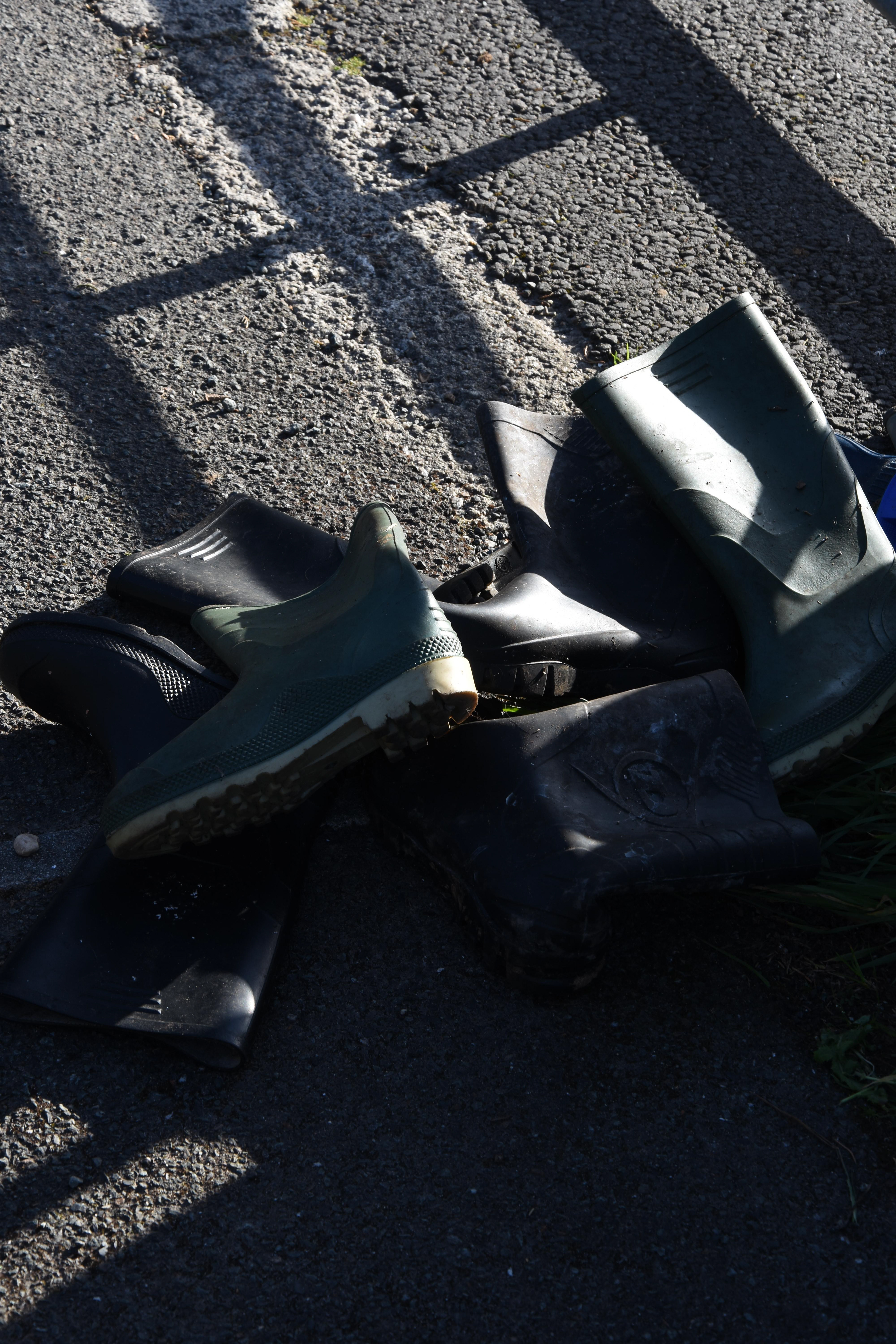 light and shadow on wellington boots on pavement documentary photography by melissa carne